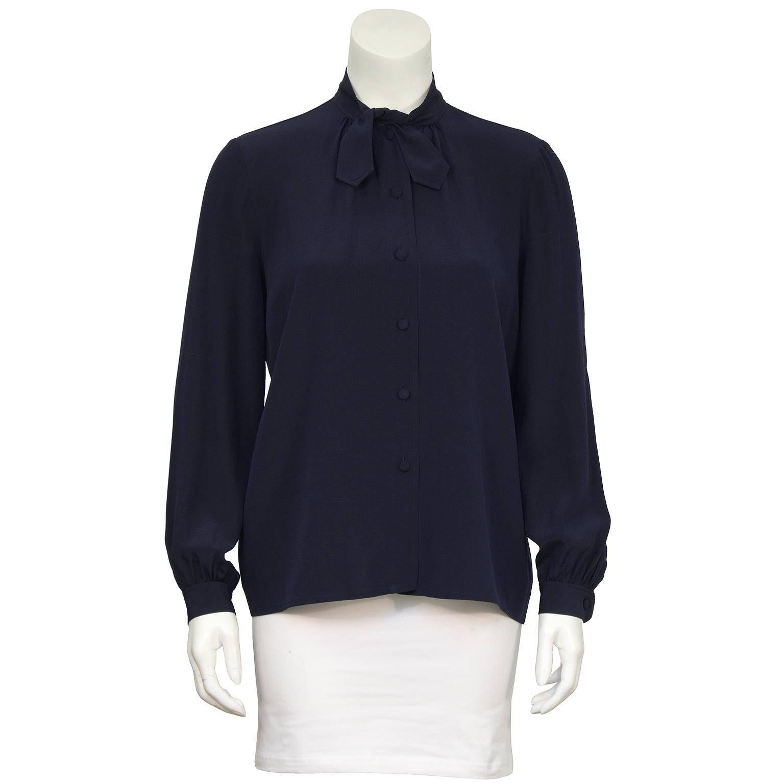 1970’s navy silk blouse labeled Chanel Creations. The blouse has a short tie at the neck and buttons up the front with matching fabric covered buttons. The sleeves have a slight puff at the buttoned cuff. In excellent condition, fits like a US 4. 

