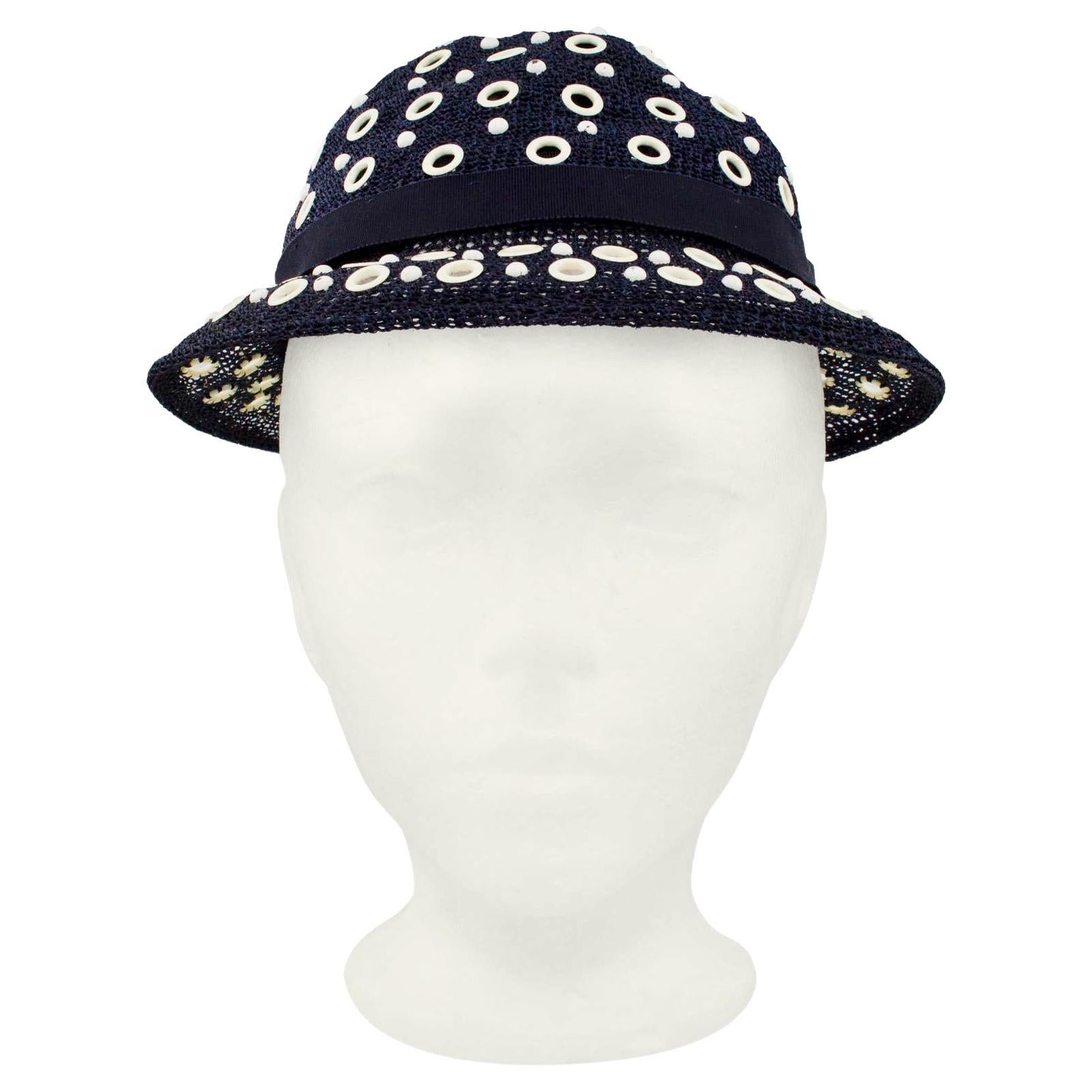 Very charming 1950s bowler style hat from Canadian luxury retailer Holt Renfrew. Navy blue mesh with all over contrasting off white grommets. Accented with a navy blue grosgrain ribbon with a bow at centre back. The hat is quite shallow and sits
