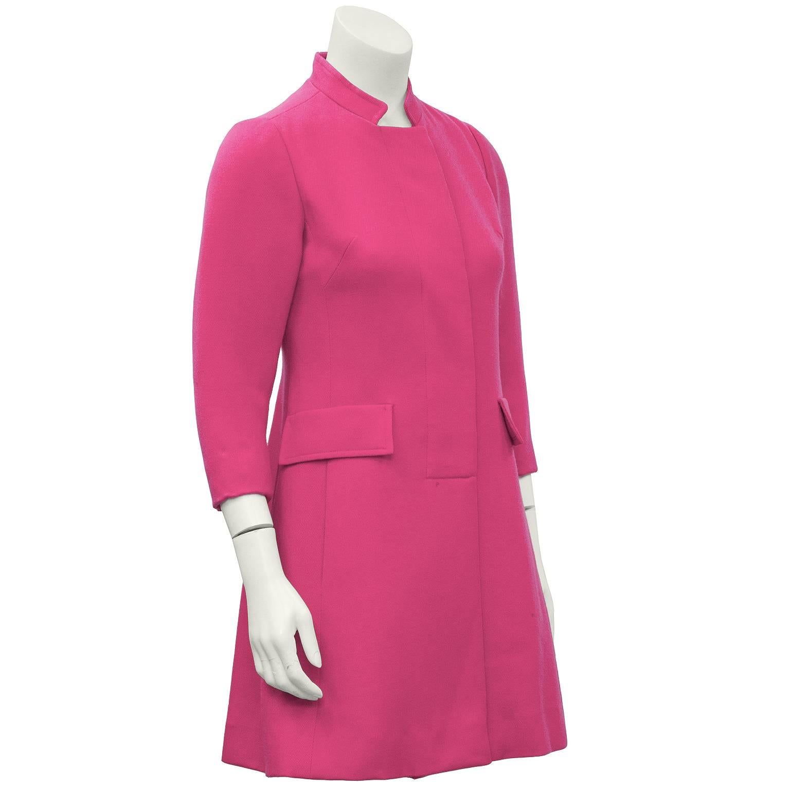 Canadian designer John Warden hot pink wool mini gabardine A-line coat from the 1960’s. The coat has a mandarin style collar and closes with large white buttons that are hidden behind a placket. Bracelet length sleeves, darts at the bust and faux