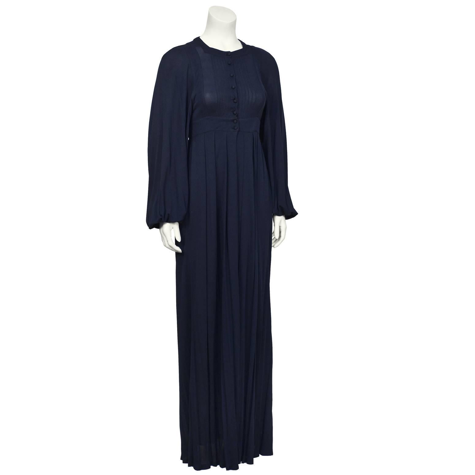 Jean Muir navy rayon jersey long sleeve maxi dress from the 1970’s. Round neckline buttons down the front with a pin tucked bib detail. The banded waist gives the dress definition and the fluid skirt falls to the ground. The sleeves are full and