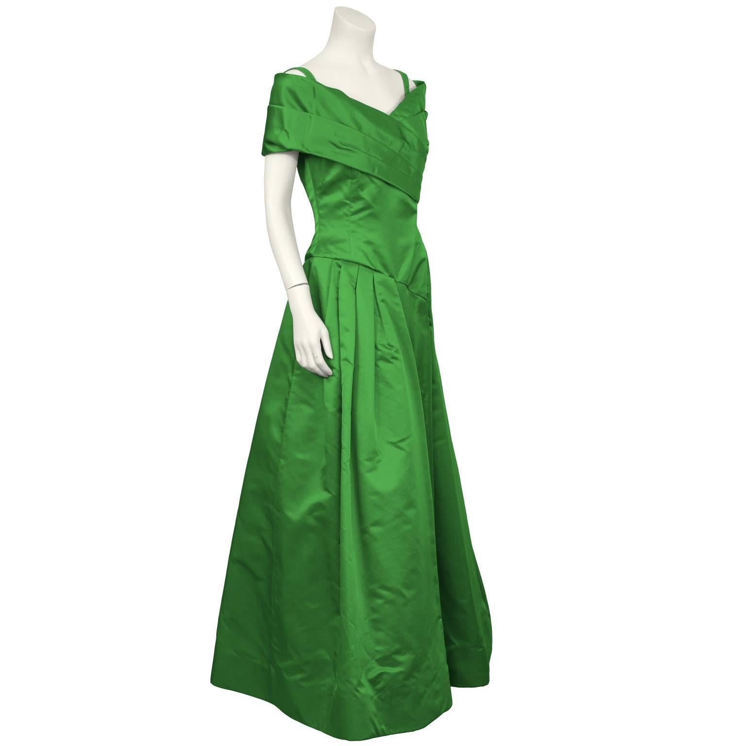Dramatic 1980's emerald green satin gown by Arnold Scaasi. The dress has a pleated off the shoulder detail that wraps around the front bust. The asymmetrical waistline has gathering on the right hip and the full skirt falls to the ground. Thin