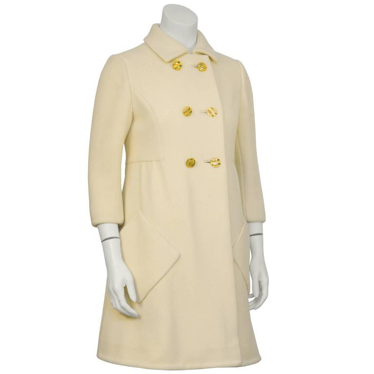 Adorable 1960's cream wool Mod style coat with double breasted gold buttons. Sweet A-line silhouette with gathering at the side and inverted pleat at the back. Bracelet length sleeves, hidden snaps at the collar, diagonal front patch pockets on the