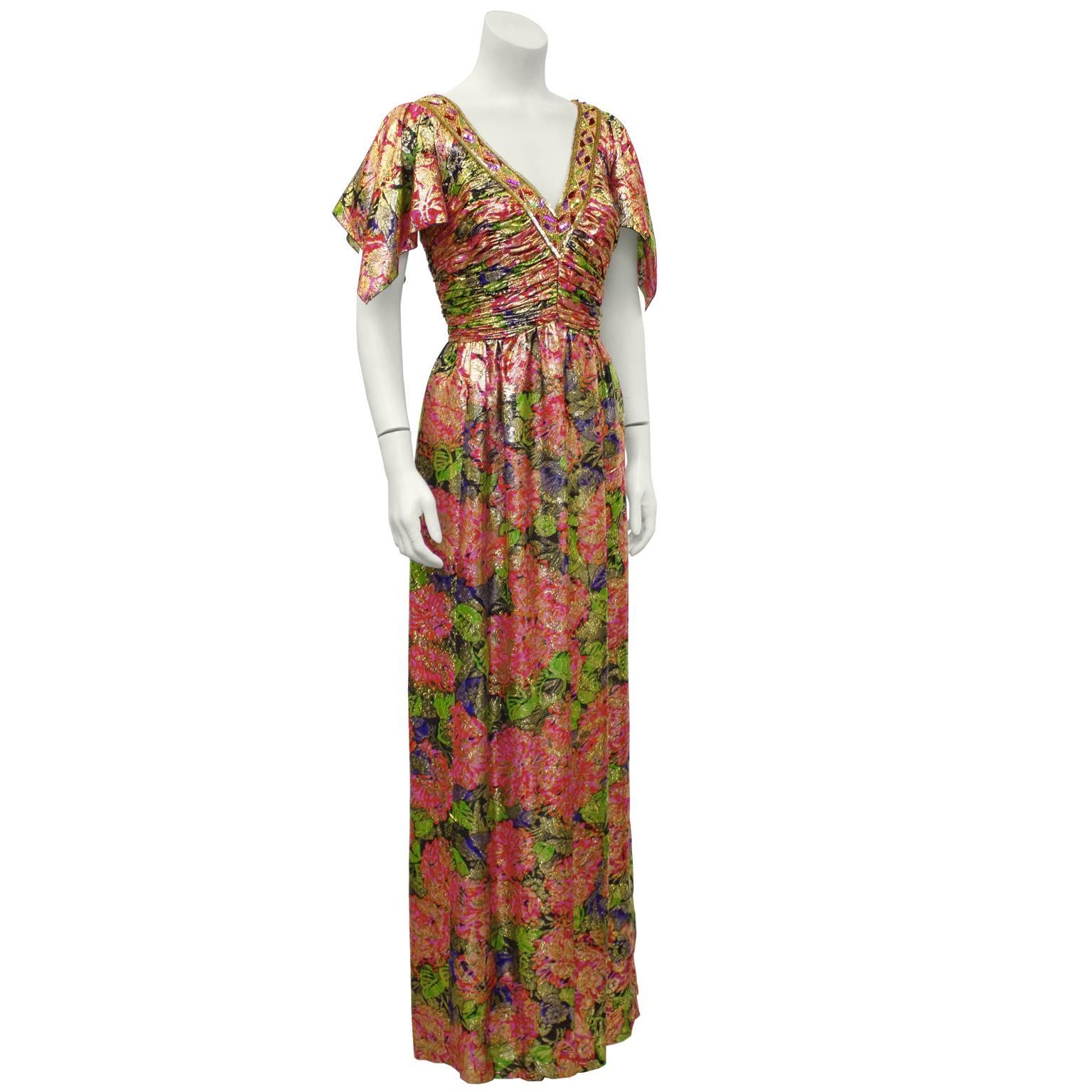 Floral pink and gold brocade Moroccan inspired gown from the 1970's. The gown features a V neckline adorned with a bead and sequin band. The bodice is ruched with sleeves finished hanky style. The skirt falls from the natural waist with a soft