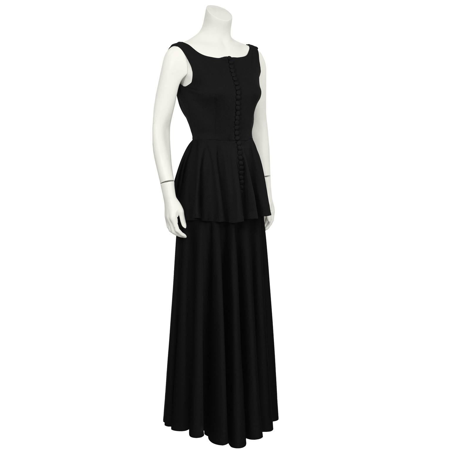 Gorgeous black jersey gown with peplum by English designer Jean Varon from the 1960's. The gown has a boat style neckline and does up the front with multiple fabric covered buttons. Dramatic cowl in the back offsets this dress's demure neckline.