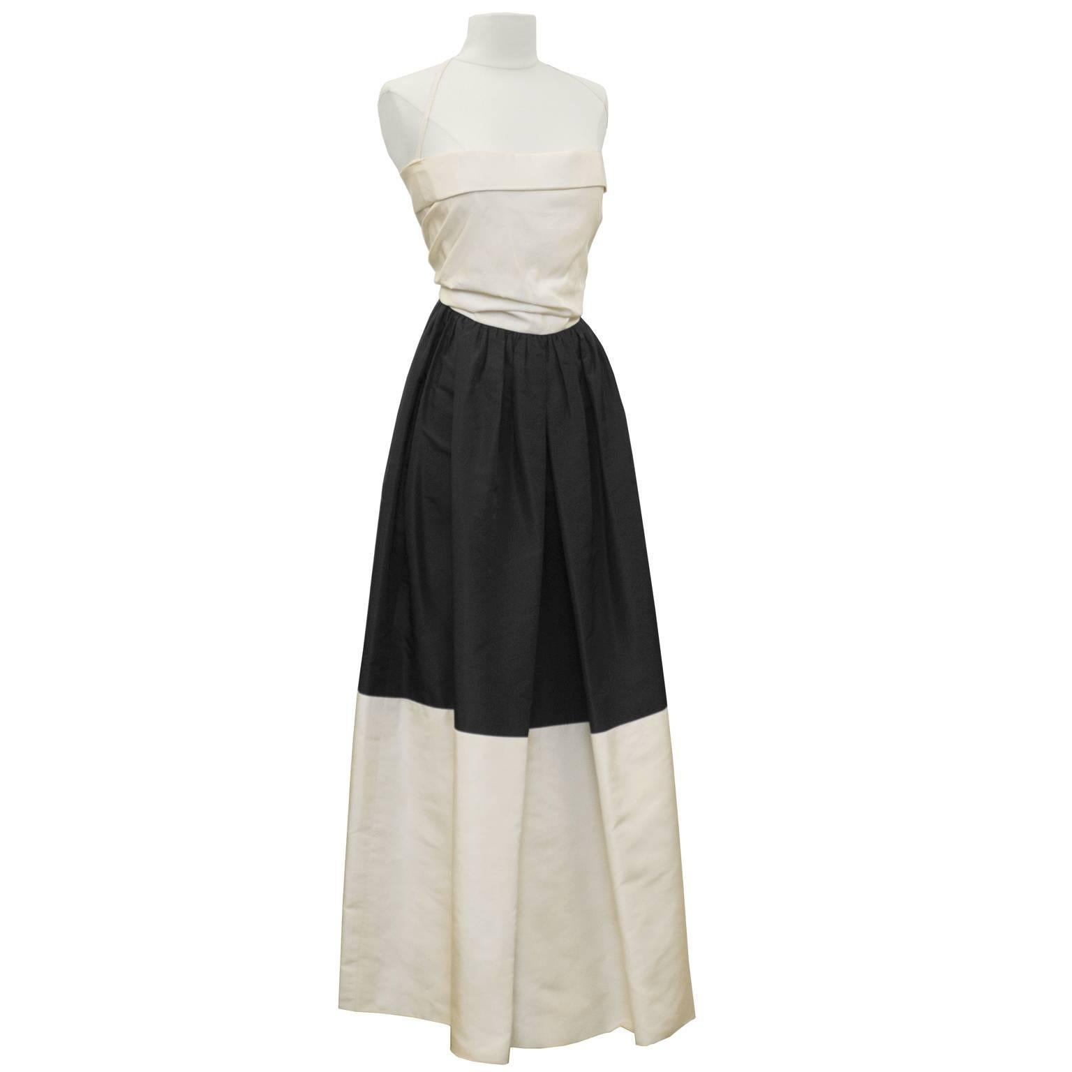 Elegant early 1960's black and cream silk taffeta strapless gown by Pauline Trigere. The gown is colorblocked with a cream bodice, black top skirt and cream hem. The top of the bodice has a single fold all around and there is a halter style strap