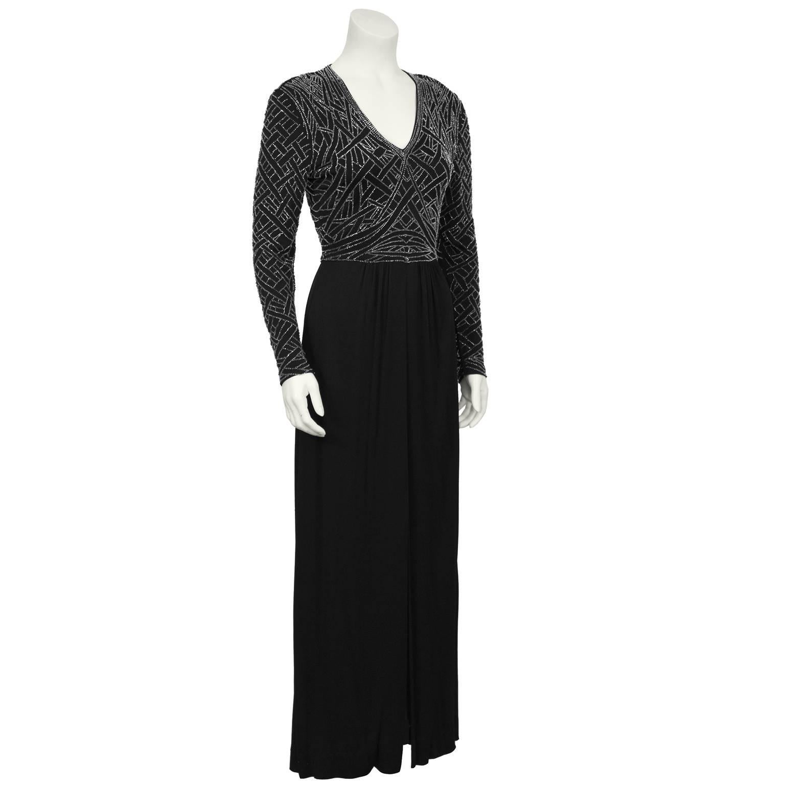 Black jersey long sleeve gown with a silver beaded bodice from the 1970's by  Hong Kong Victoria Royal. The gown has a V neckline and the bodice is beaded all over with silver beads in an abstract geometric pattern. The loosely gathered polyester