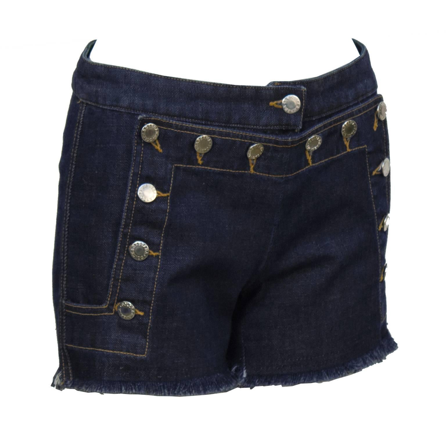 Flirty denim shorts by Dolce & Gabbana from the 1990's. The shorts do up sailor style at the front with silver Dolce & Gabbana logo buttons. Cut off frayed hem and black lace up detail on the back makes these perfect for the summer. In excellent