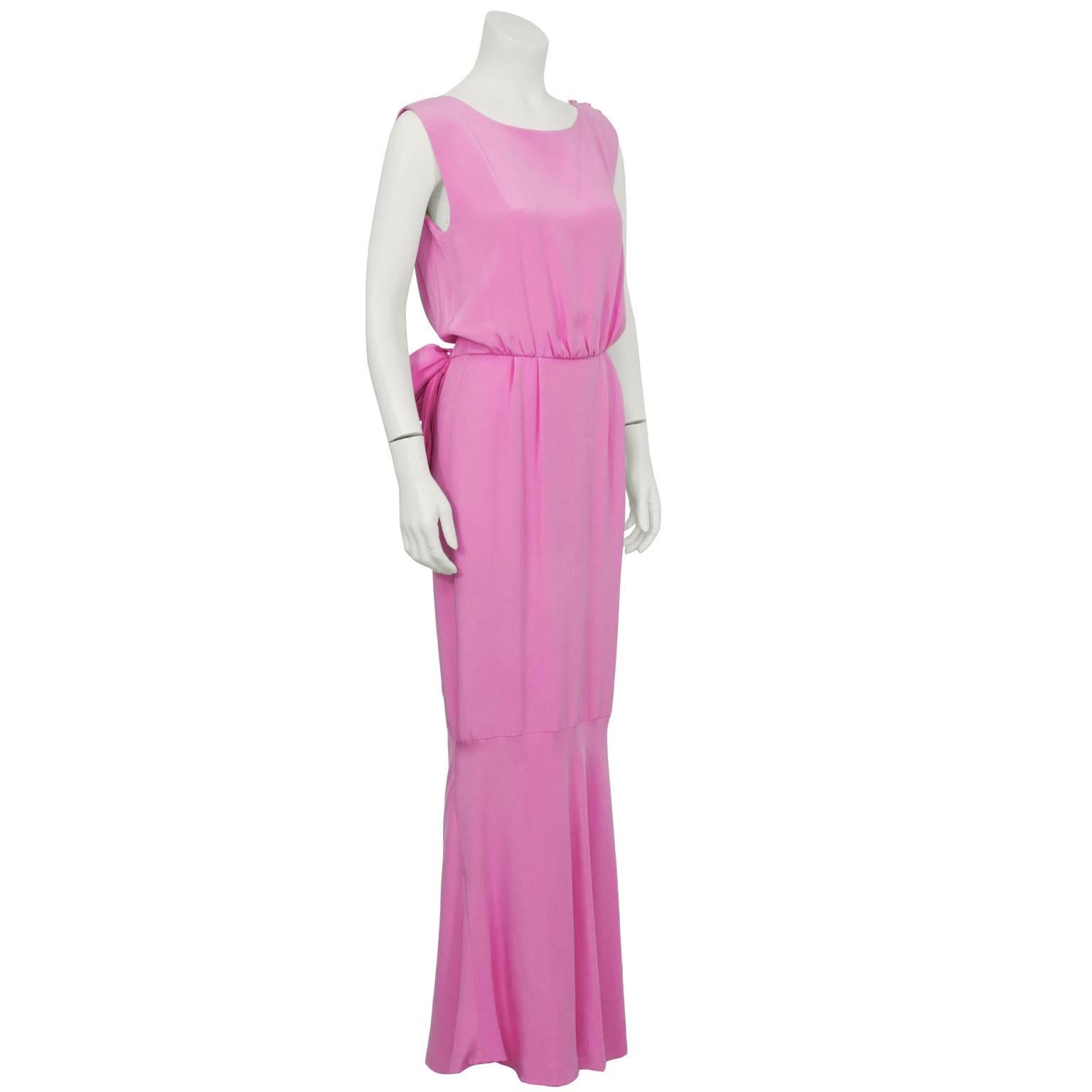 Shocking pink silk evening gown from the 1960's. Gathering at shoulders and natural waist, creating a flattering silhouette. The front is simple with a high neckline, the back has a low cross over V neck detail with a bow and tulip style overlay on