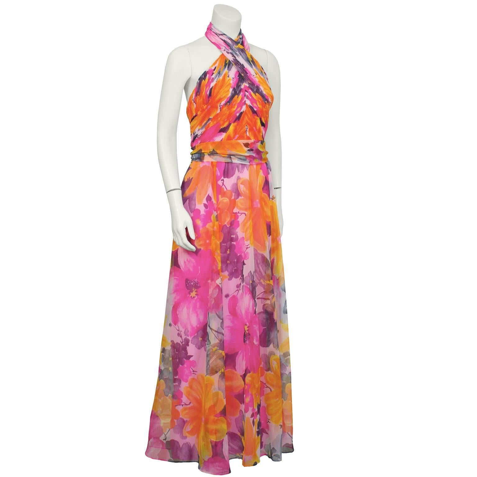1970's fun and flirty polyester blend hot pink floral halter gown. The bodice is ruched and the skirt falls from the natural waist. Attached sash at the waist, zips up the back with hooks at the neck. Fully lined in hot pink silk blend material. In