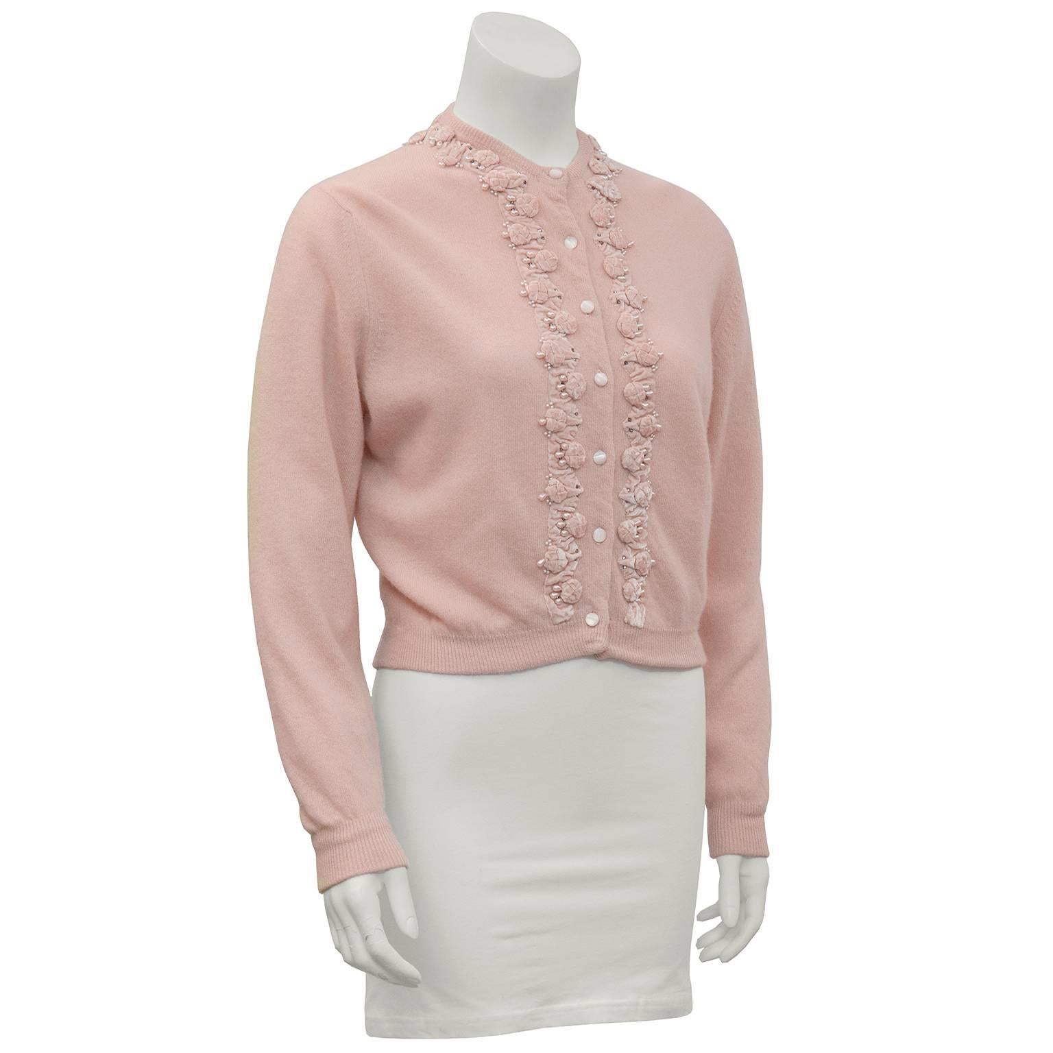 1950's pink cashmere cardigan with matching pink velvet ribbon and pearl motif sewn on the front and cuffs. Just like everyone's aunties used to wear back in the day! Lined with silk, mother-of- pearl buttons, Drape over shoulders and a rocker Tee.