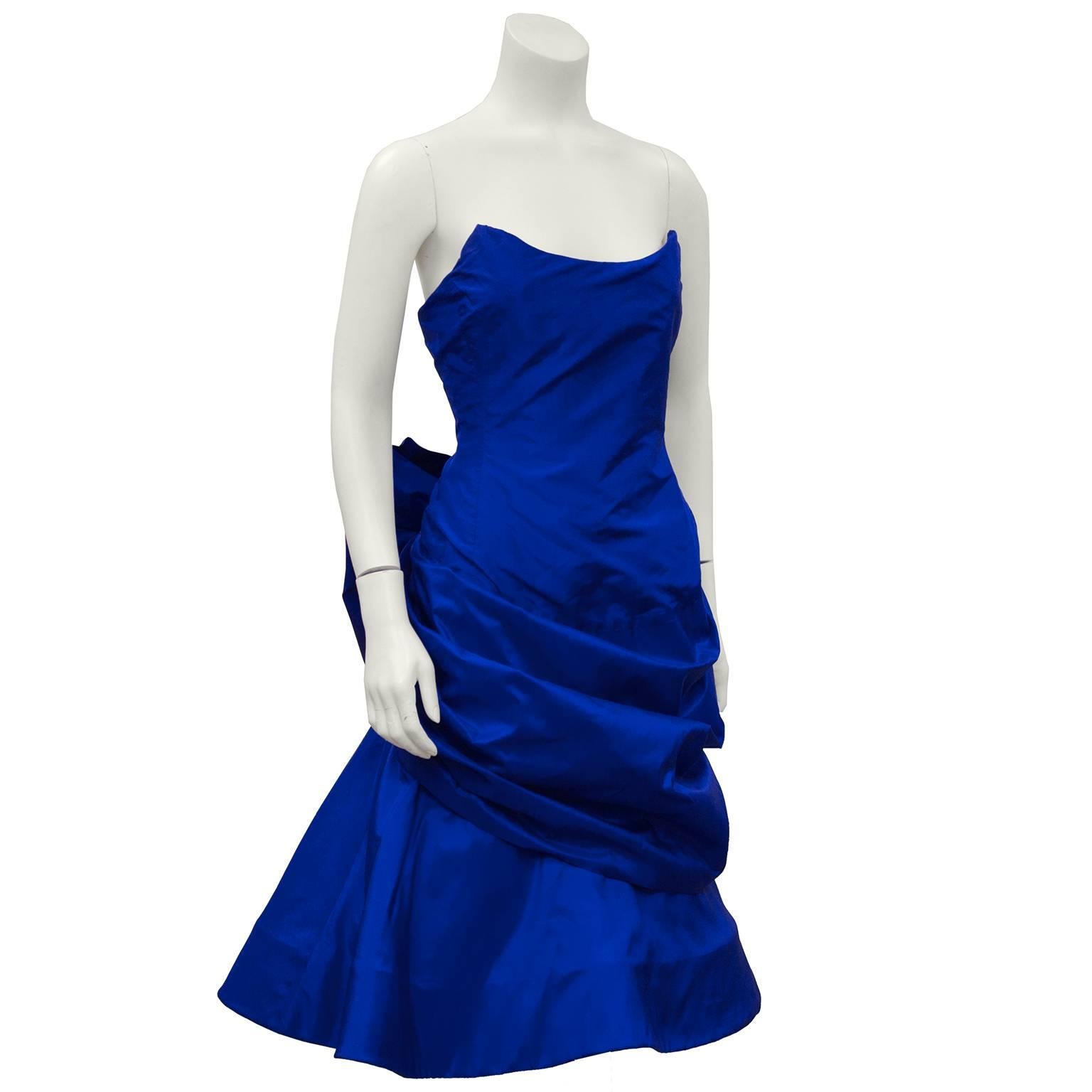 1980's royal blue silk taffeta fitted strapless cocktail dress by Arnold Scaasi. The neckline is very architectural and finishes with two points. The front is fitted across the bodice and gathers around the hips while the bottom skirt layer poufs