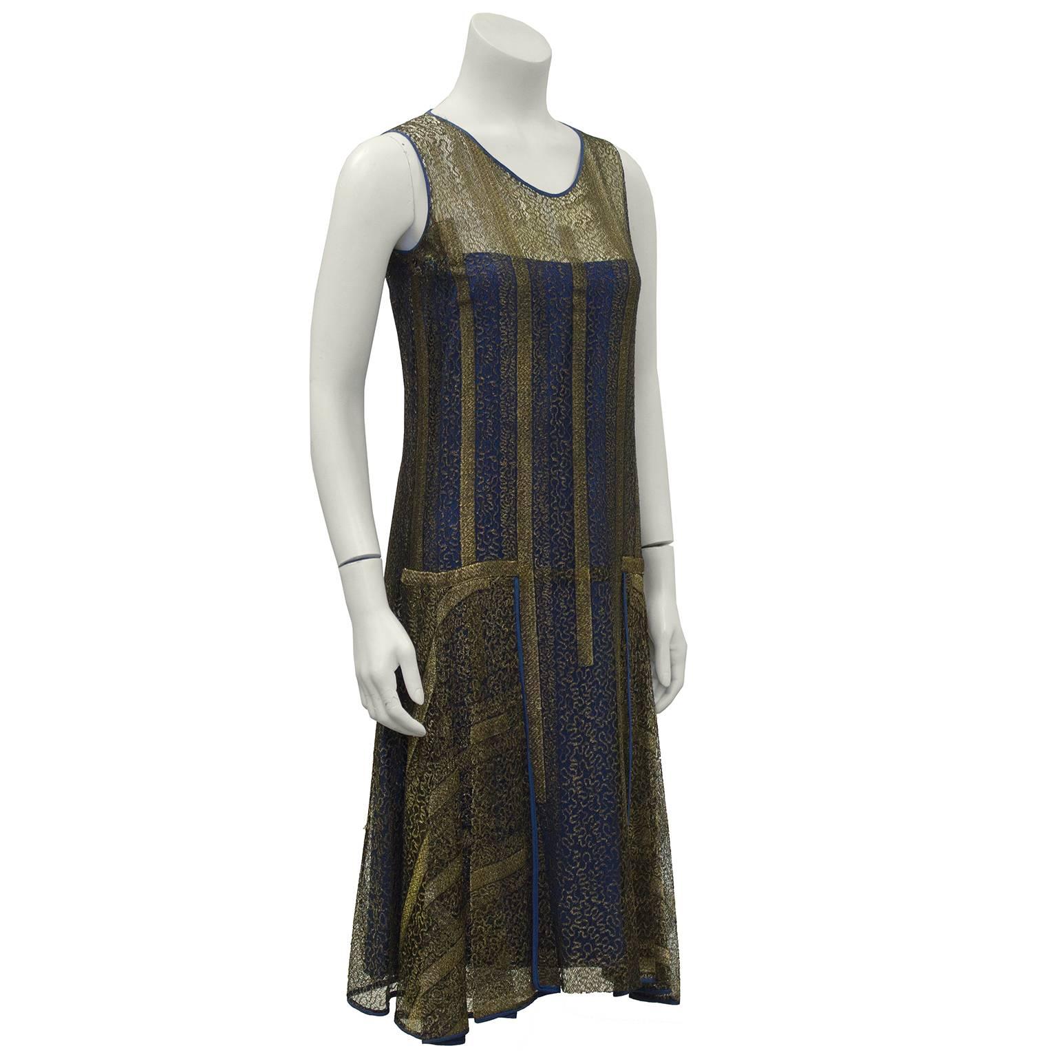 Art Deco era gold lace overlay flapper style dress from the 1920's. The navy silk under layer is attached to the gold lace over layer from the bust to the hem. Lace layer covers the whole topside of the dress from the round neckline down. The lace