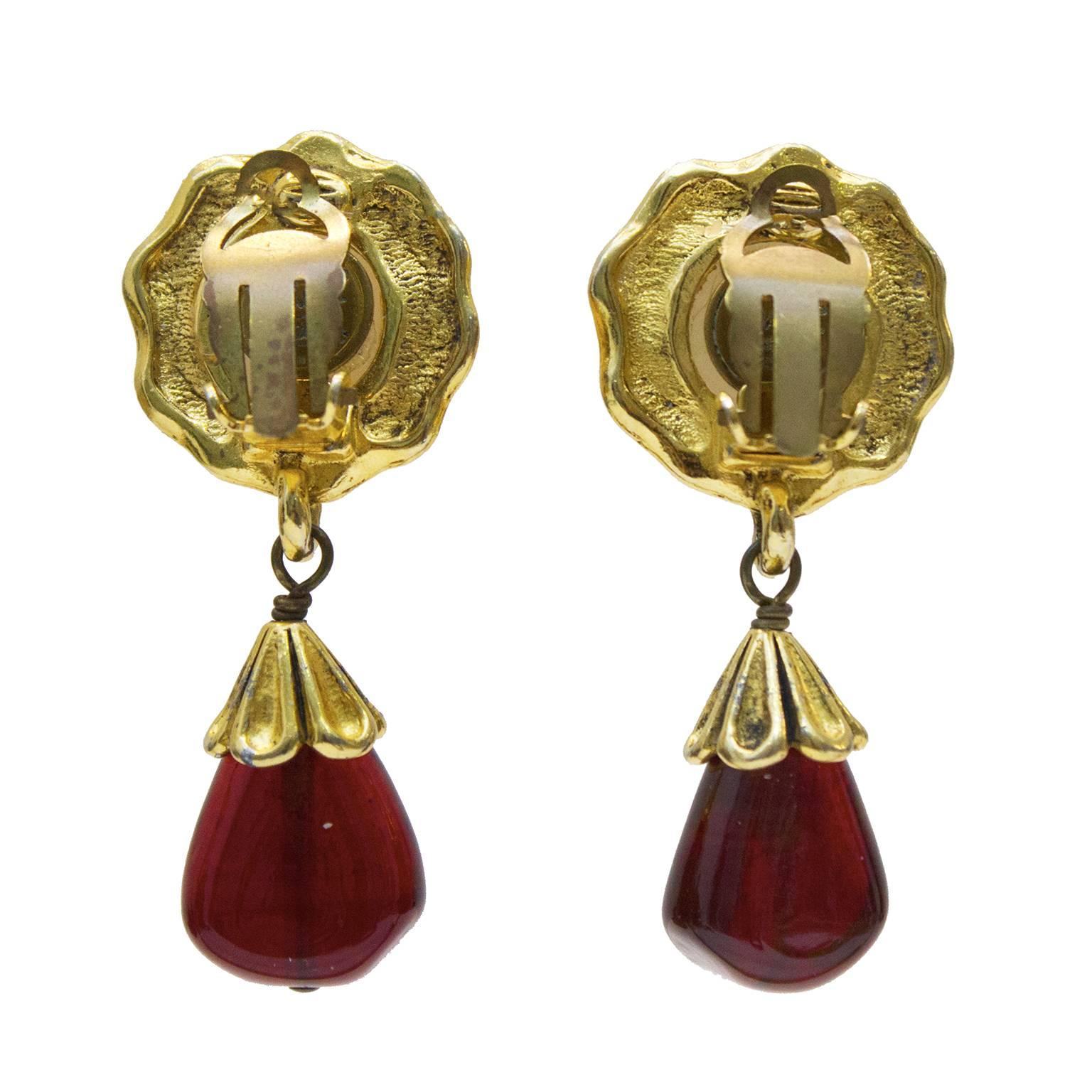 Chanel pearl and poured glass earrings from the early 1980's. The clip on style earrings are comprised of a faux pearl  surrounded with gold hardware and a red poured glass drop attached with a goldtone topper. In very good vintage condition with