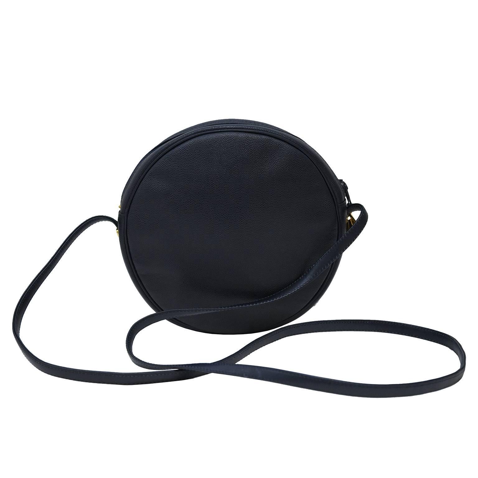 Midnight blue pebbled leather round crossbody bag by Karl Lagerfeld from the 1980's. Zip top closure goldtone fan shaped pull tab, goldtone logo hardware affixed to the front of the bag above a single open front pocket and goldtone rivets along the