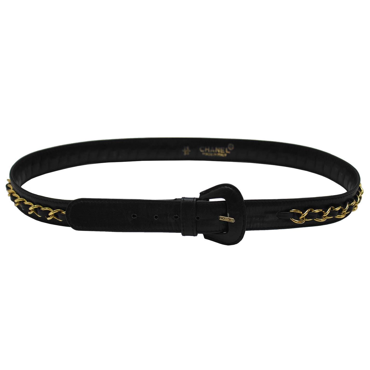 Classic Chanel black leather skinny belt with attached goldtone chain with woven leather detail. Leather covered buckle frame with CHANEL stamped on the goldtone prong. Meant to be worn cinched at the waist, stamped CHANEL on the inside of the belt