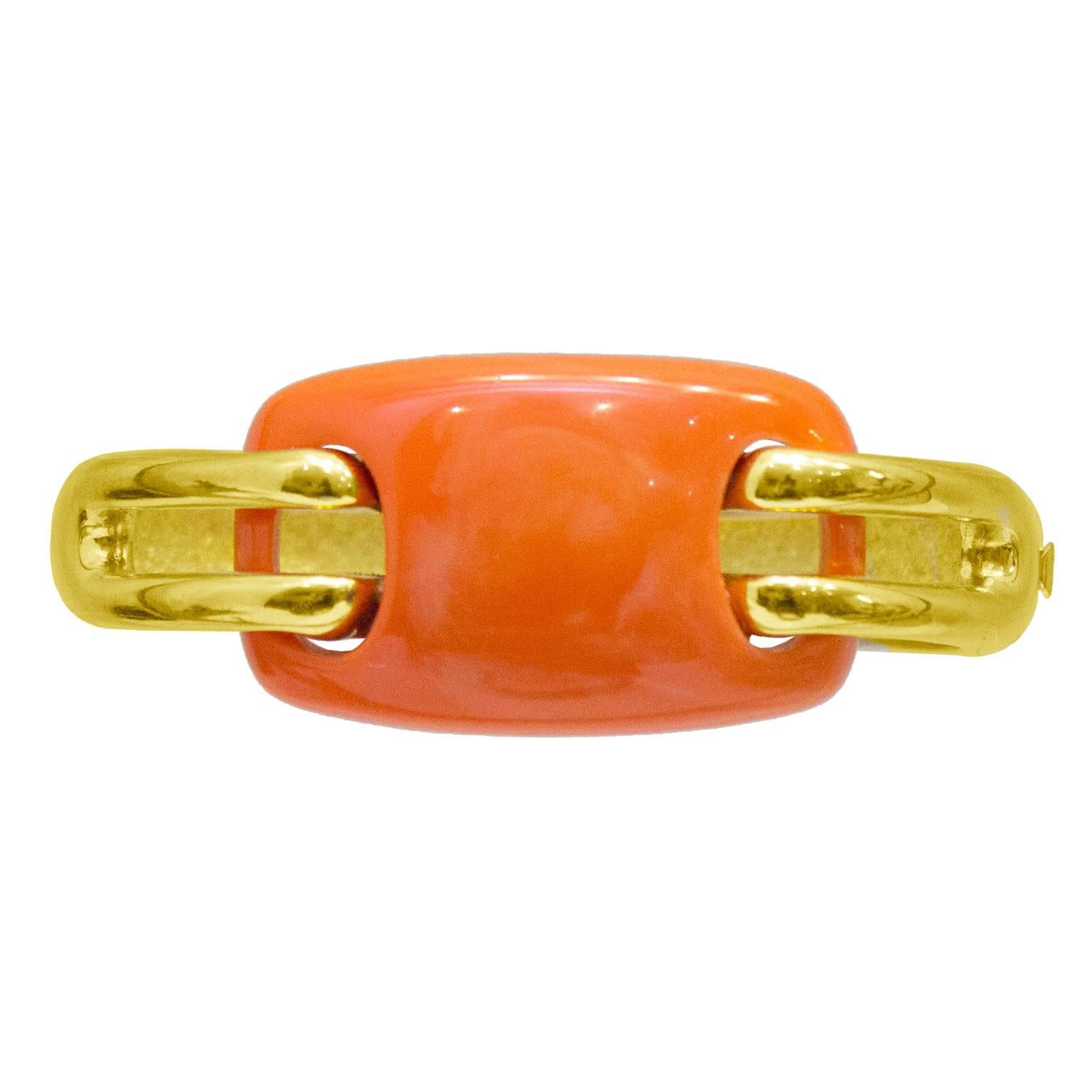 Modern and minimalist 1976 Givenchy faux coral and gilt metal bangle. Simple rounded and curved rectangular coral lozenge appears woven onto the solid gilt metal bangle through 2 side bars. Closes on the wrist with a release tab and hinge. Signed