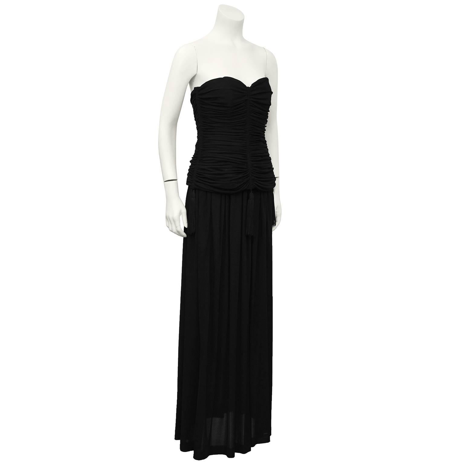 Classic 1980's YSL/Yves Saint Laurent black strapless jersey 2 piece gown with black hanging tassel details. Ruched boned and structured strapless top has strategically placed long tassels along the hem. Elasticized waist skirt has a soft drape and