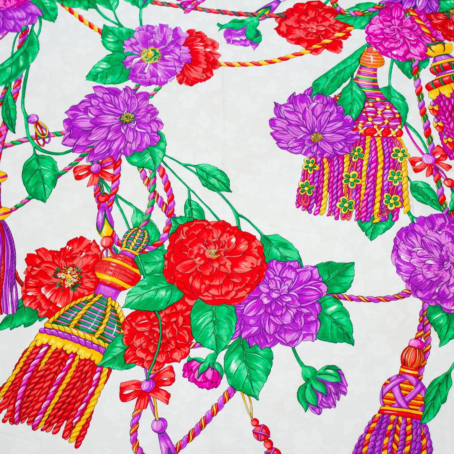 Vibrant colored 1980's silk jacquard scarf by Balenciaga. White background with purple, red, green and yellow floral and tassel design. Black border with white Balenciaga signature. Hand rolled edges. In excellent condition. 35