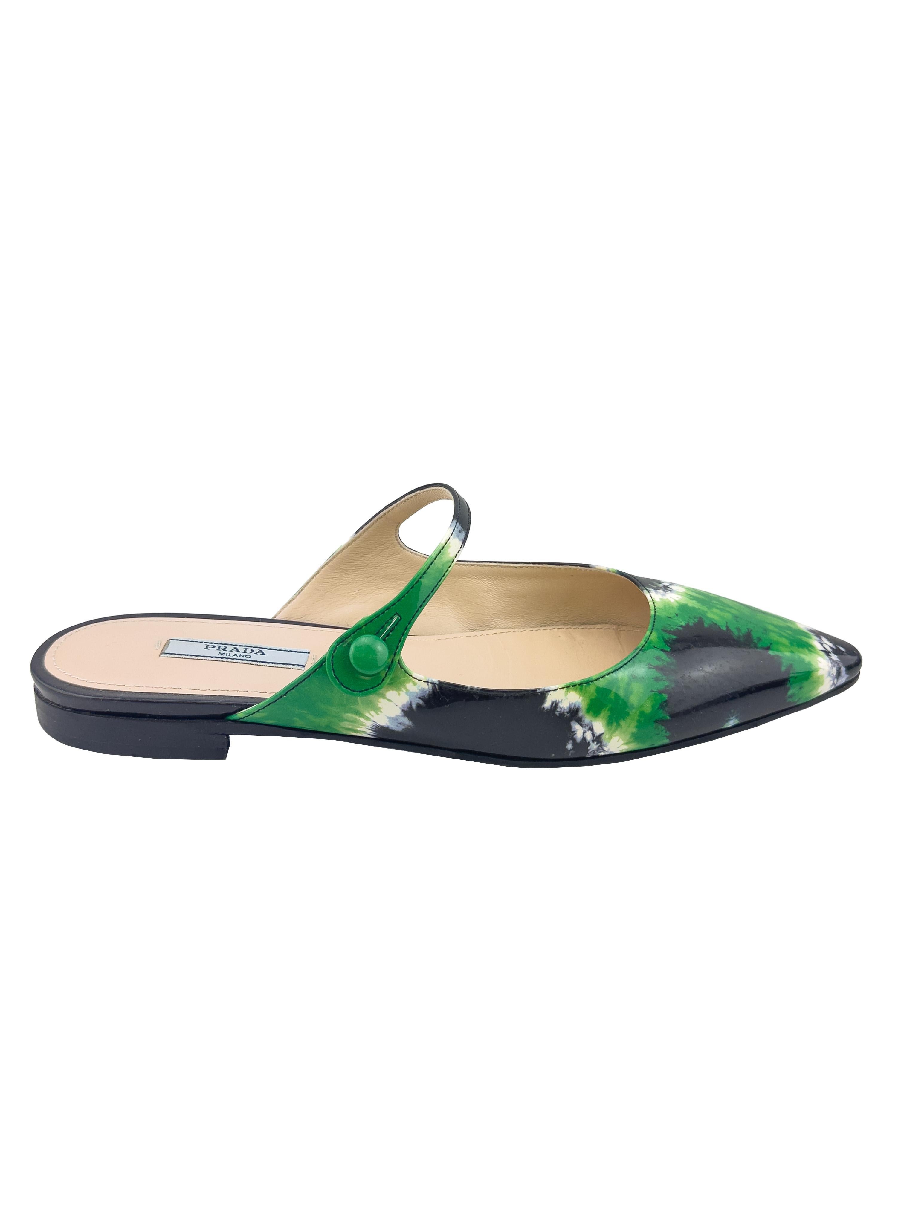 Mules plates Prada issues de la collection printemps/été 2019. Cuir verni noir et vert vif tie dye. Bout pointu arrondi et fine bride sur la voûte plantaire avec un petit bouton vert. Une forme rétro classique avec un design moderne. Excellent état