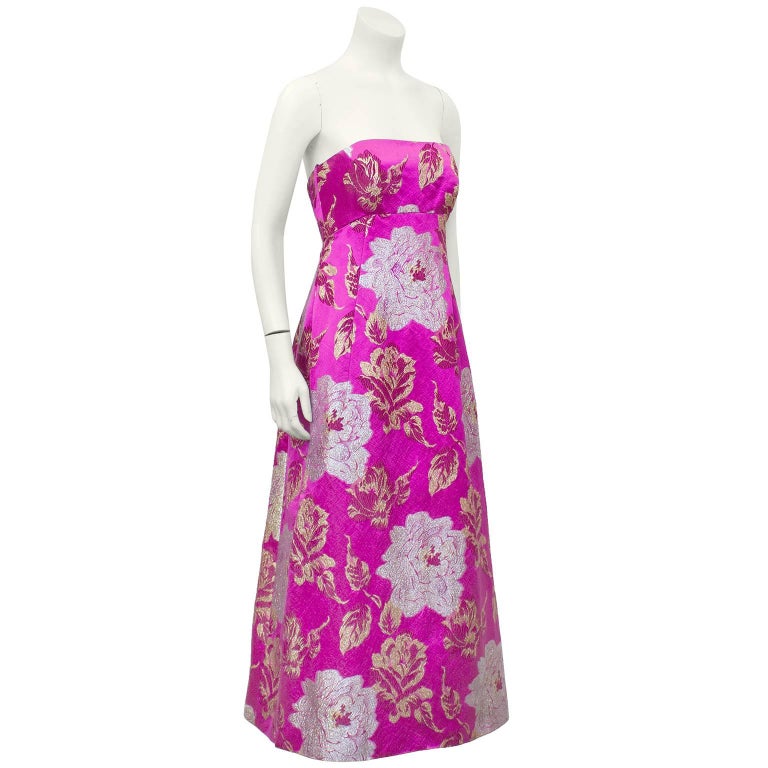 Stunning 1960's Malcolm Starr strapless, empire waist, tea length evening gown. Magenta with metallic brocade rose pattern throughout. The simple and timeless shape, combined with such an amazing colour create a breathtaking garment. Very current.