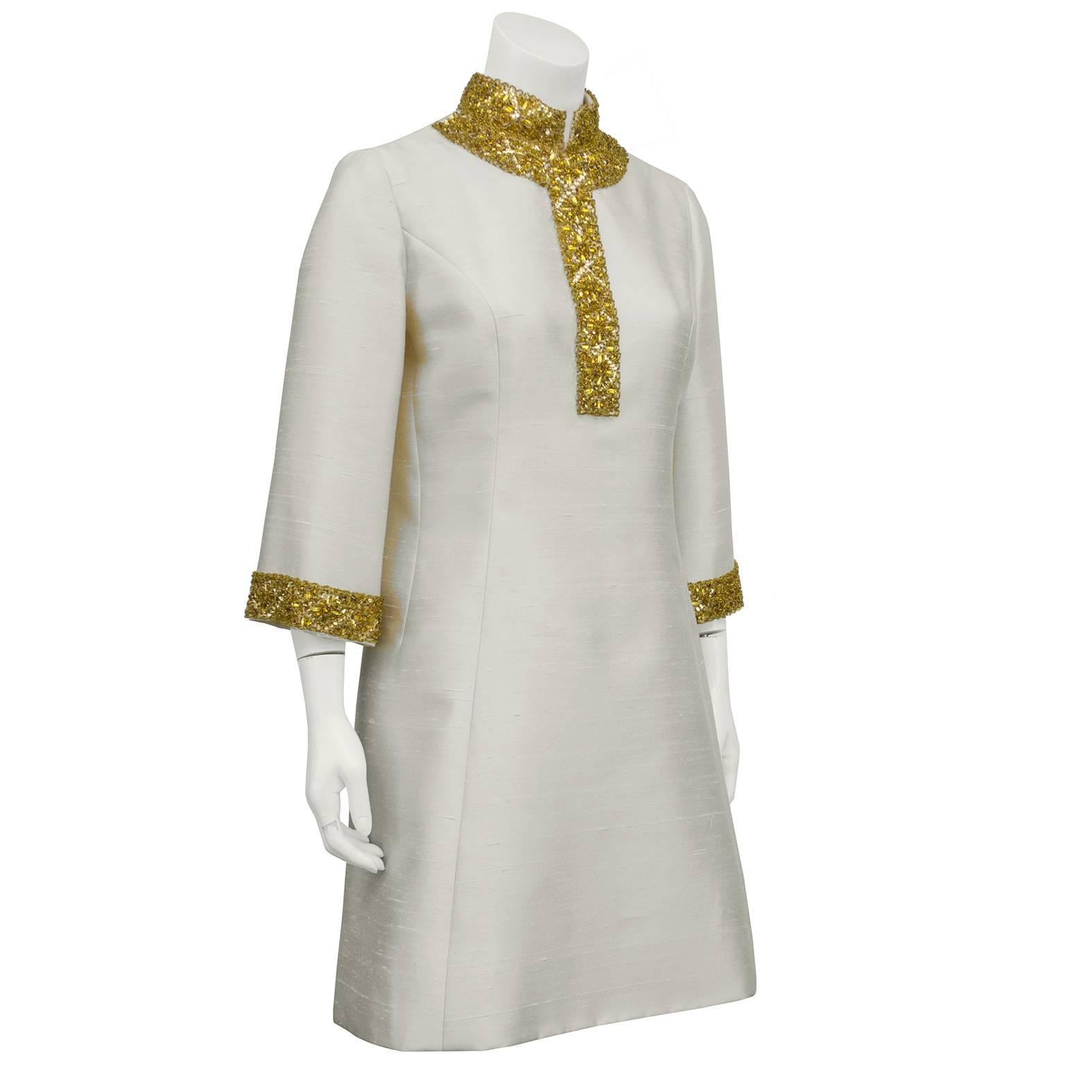 Shaped like an updated and flattering caftan, this 1960s cream raw silk dress has the most beautiful gold beading detail along the neckline and cuffs. Seaming down the side creates a beautiful silhouette and a zipper up the back makes for easy