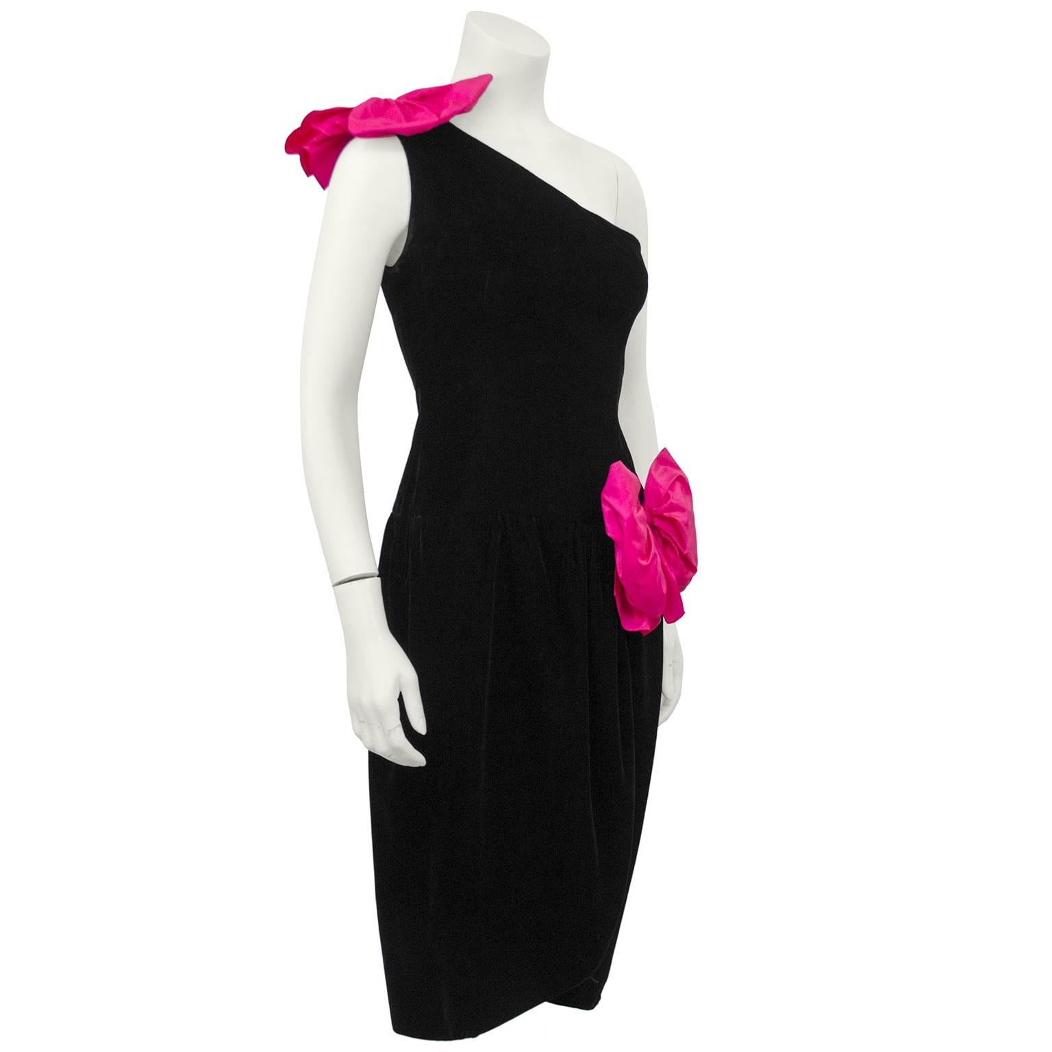 1980s Oscar de la Renta Miss O label black velvet cocktail dress with one shoulder accented with two large hot pink taffeta bows. Fitted through the body with a slightly gathered drop waist. Tulip style hemline and bow accent on the left hip and