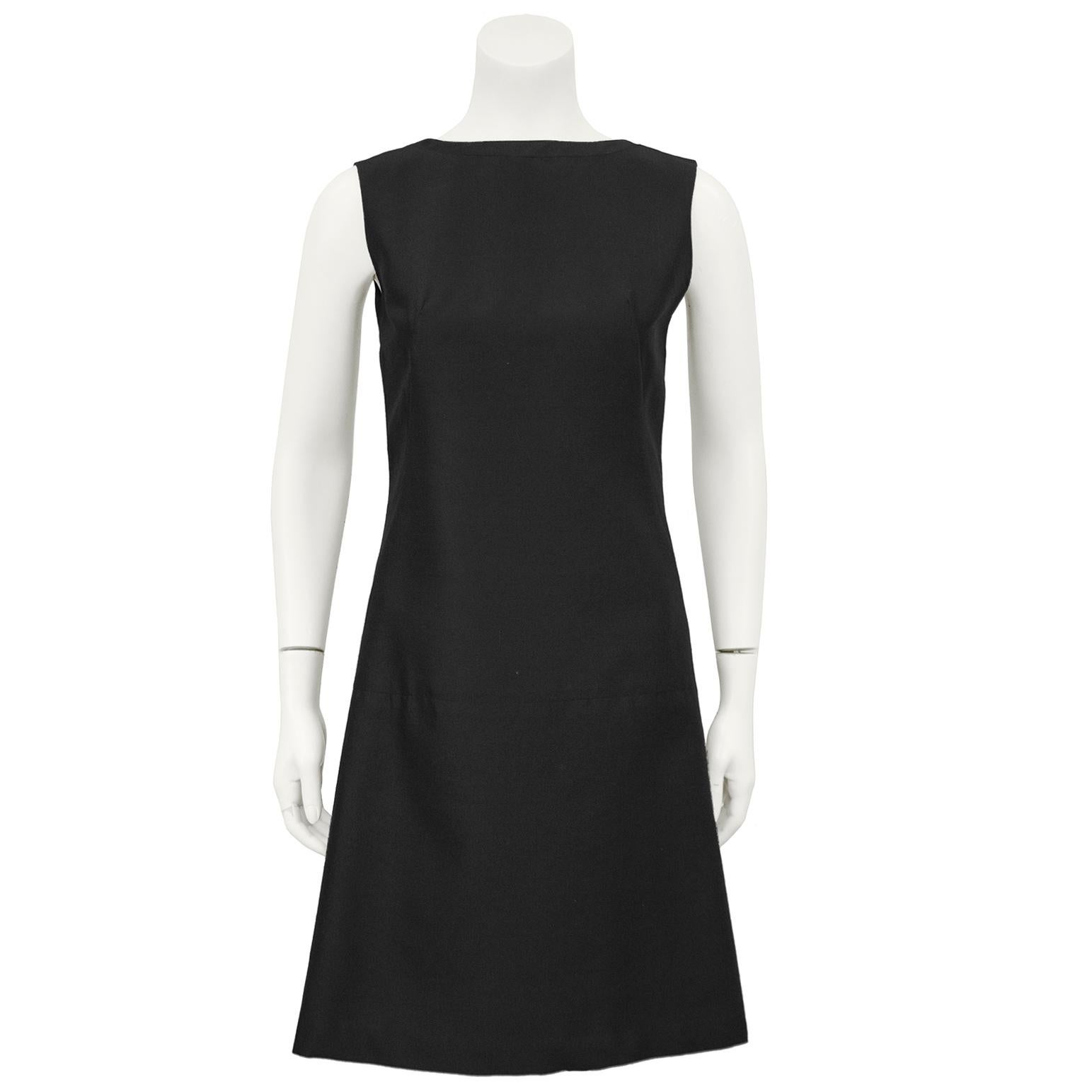 Adorable 1960s Lanz black wool shift style cocktail dress. The sleeveless dress fastens up the back with a series of hidden hooks and snaps to create a dramatic faux wrap detail accented with bows. Darts down the front of the dress, fits like a US
