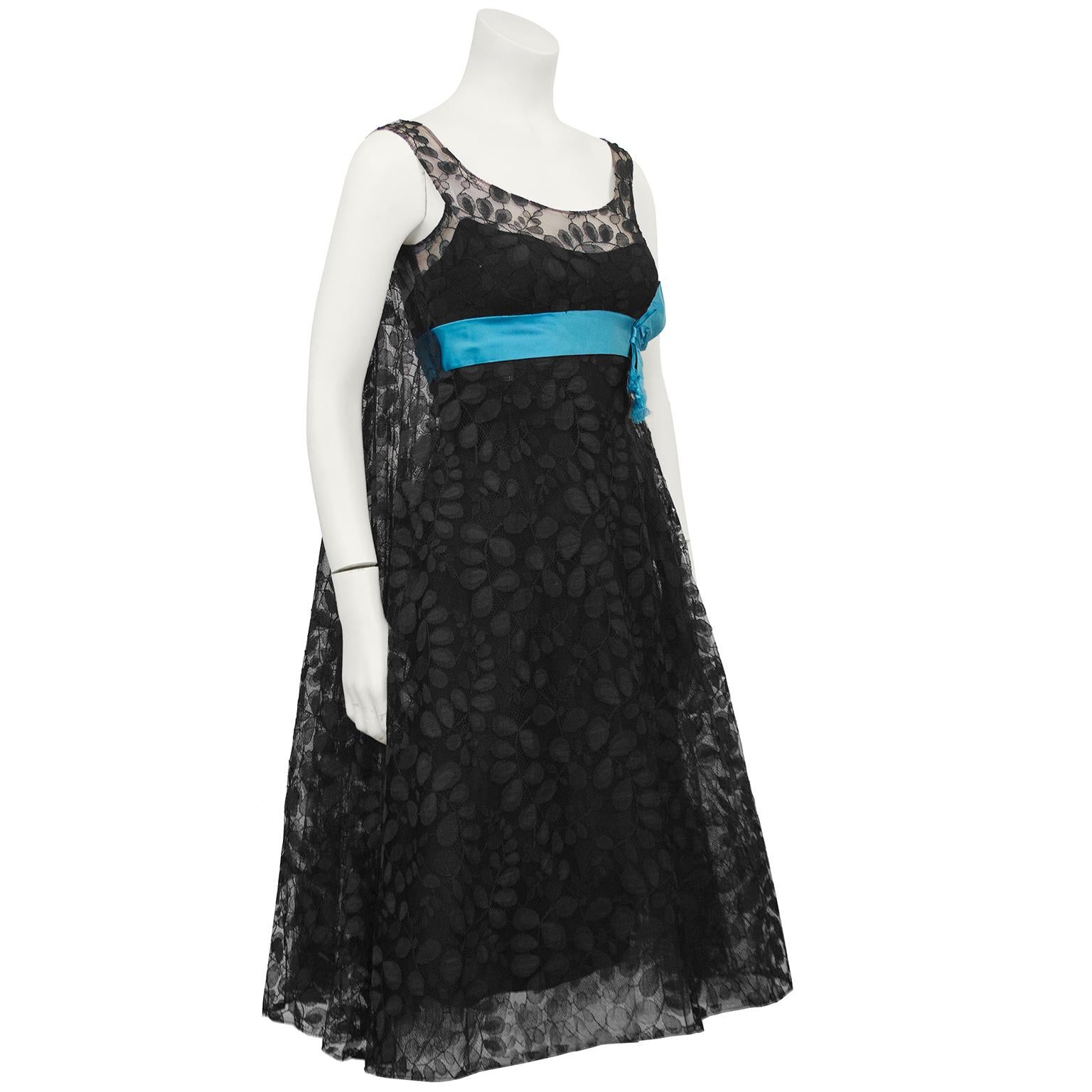 1950's black lace cocktail dress from the Saks Fifth Avenue label. The empire waistline is accentuated with an attached turquoise corded silk sash finished with an affixed bow. The dramatic back of the dress glides away in trapeze style and the