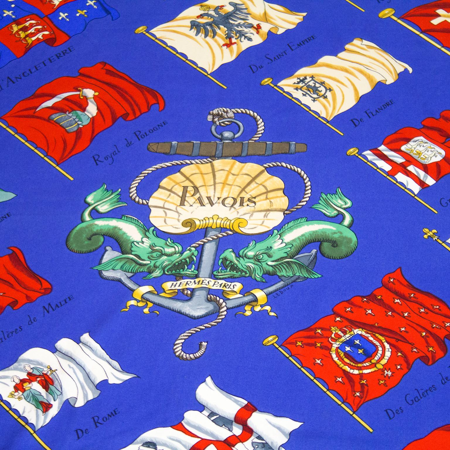 Designed by Philippe LeDoux in 1964, the scarf is a bright blue background with a multicultural nautical flag pattern surrounding an anchor with a shell, dragon fish and rope. In excellent condition, 100% silk, 35” square. Signed throughout design. 