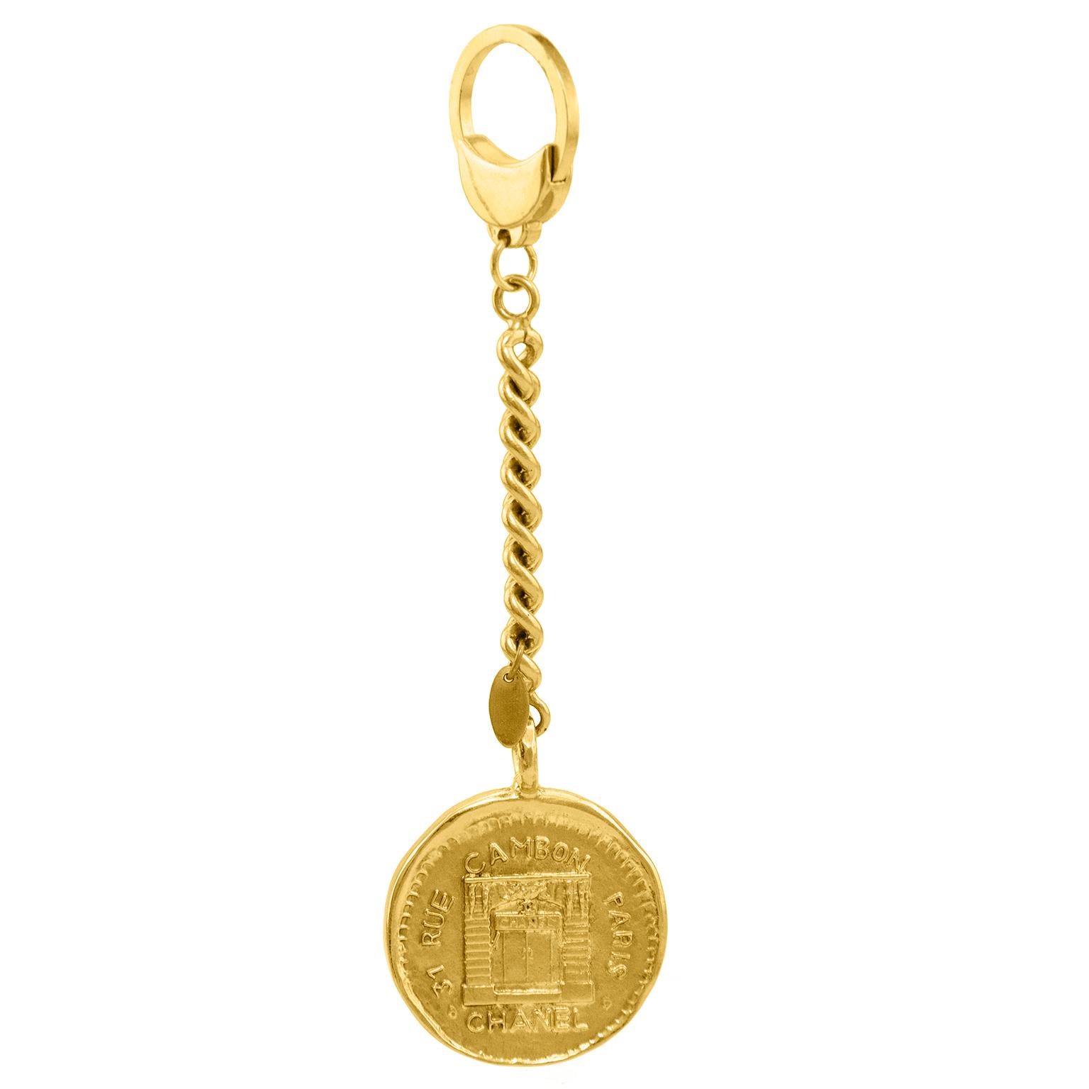 Chanel keychain dated from collection 23. The goldtone coin is stamped with the iconic Rue Cambon address and image. Rounded chainlink connects the coin to the key ring. In excellent condition.  No original box.