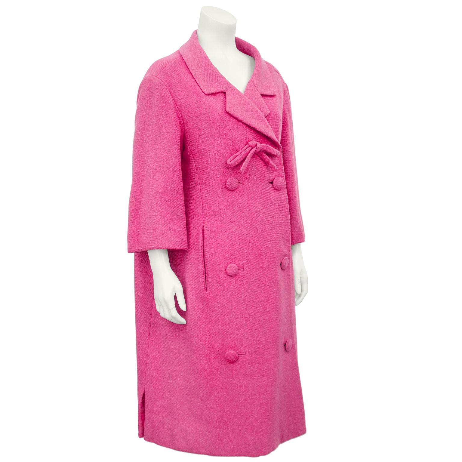 Beautiful numbered 1959 Spring collection coral pink wool coat from the house of Christian Dior designed after his passing by Yves Saint Laurent. The coat has a wide notched lapel with a bow and double breasted buttons down the front. Hidden hooks