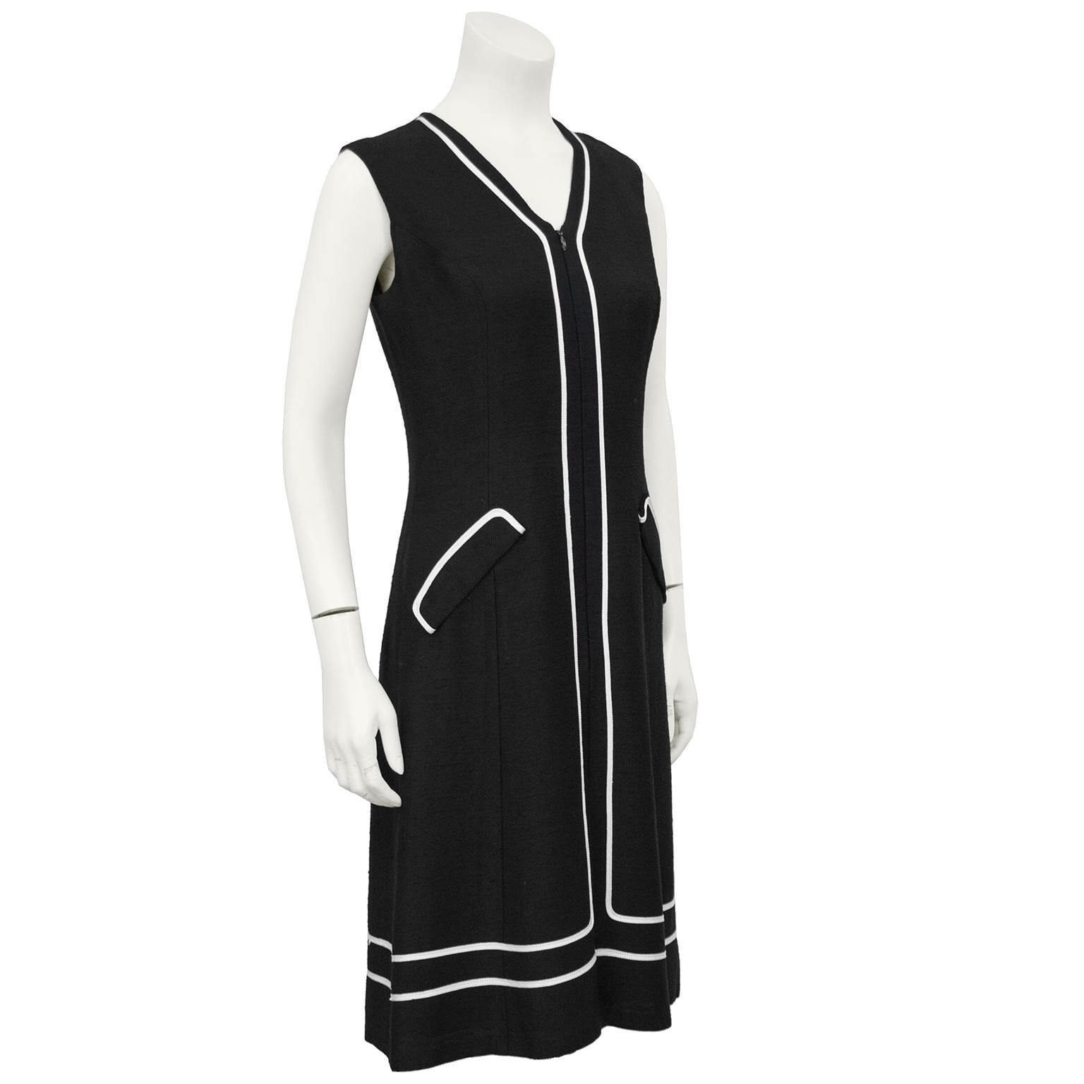 Stylish 1960s anonymous black day dress with white piping along the neckline, hemline and down the front. The dress has two faux pockets on the hips and zips up the front. Uber chic, the perfect LBDD - Little Black Day Dress. Fits a US 4. 