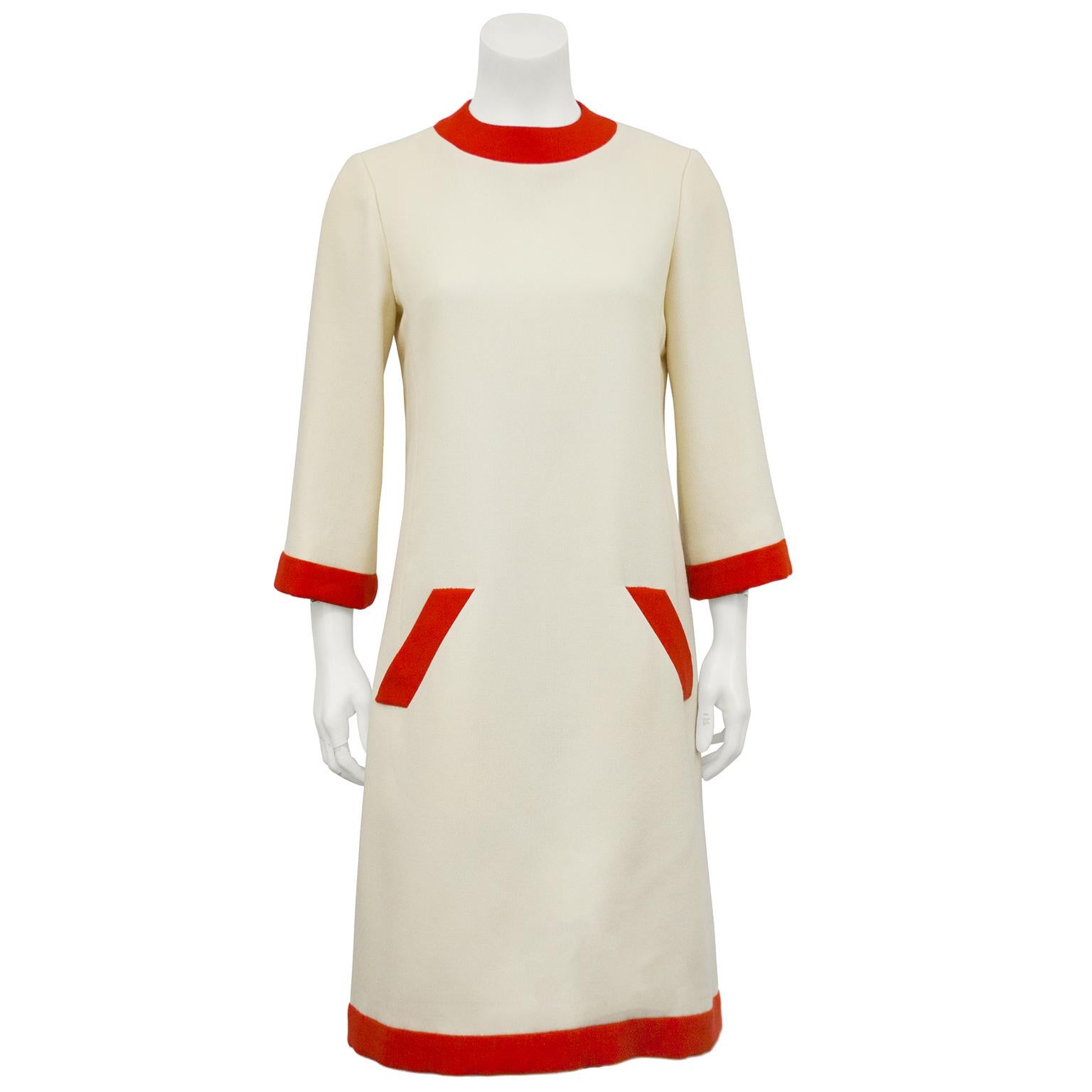Classic Geoffrey Beene cream and orange long sleeve wool day dress from the 1960s. The A line cream dress has bell style sleeves and is accented with bold stripes of orange at the neckline, cuffs, hemline and along the diagonal side slit pockets.