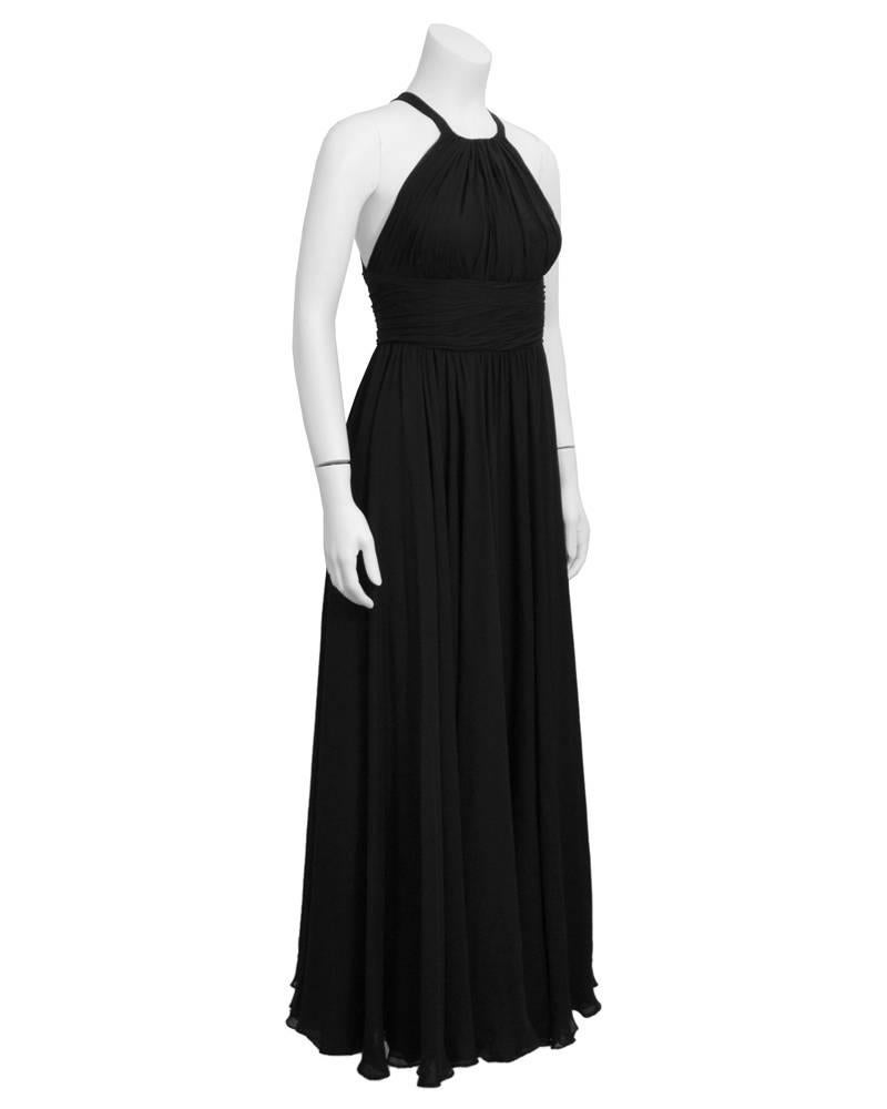 Stunning and elegant late 1960's Galanos couture black silk chiffon gown. Fitted halter style bodice with vertical gathering at bust and horizontal gathers across waist. Halter straps cross at upper back, creating a beautiful open back. Skirt is