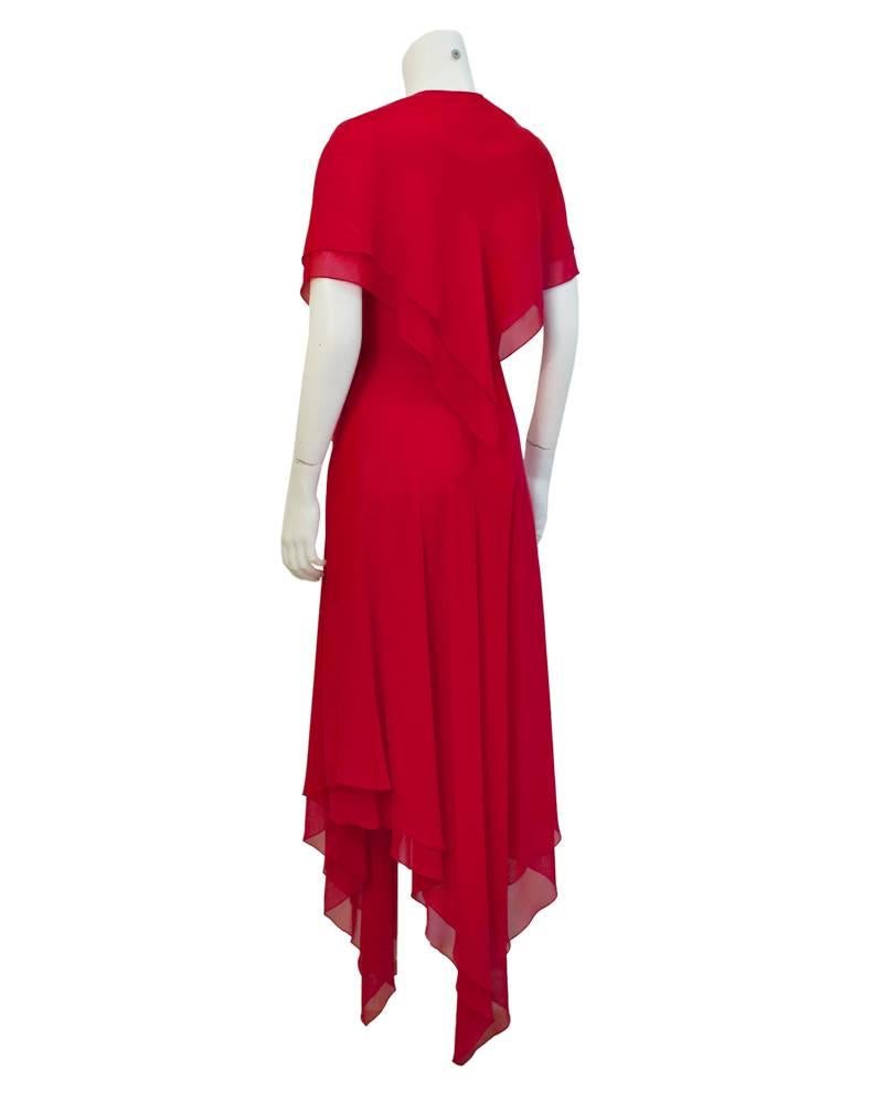 Exquisite 1960's red chiffon hanky hem gown with matching capelet. Fitted through the bodice with spaghetti straps the dress is double layered, a feature that is accented by the irregular hemline. The dress closes with a side zipper. The capelet