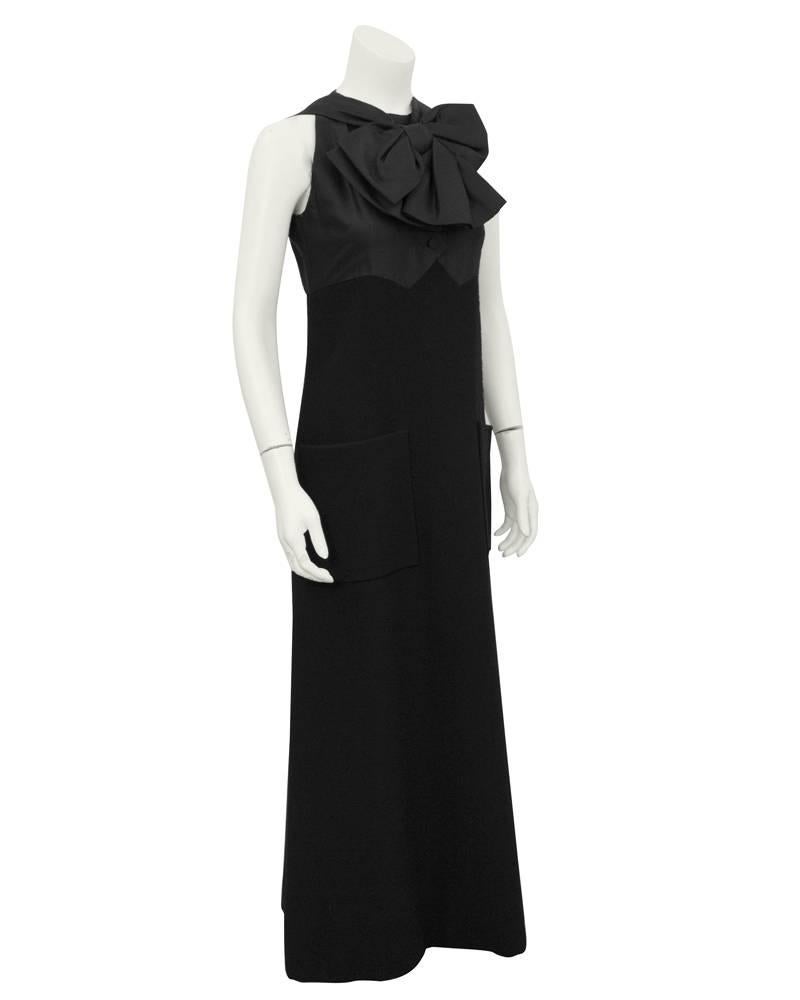 Wunderschönes schwarzes Kleid von Geoffrey Beene aus den 1960er Jahren. Schwarzes Seidenmieder mit unechten Knöpfen und einer fabelhaften großen Schleife. Der Rock ist aus Wolle und hat eine sehr leichte A-Linienform, mit zwei großen flachen Taschen