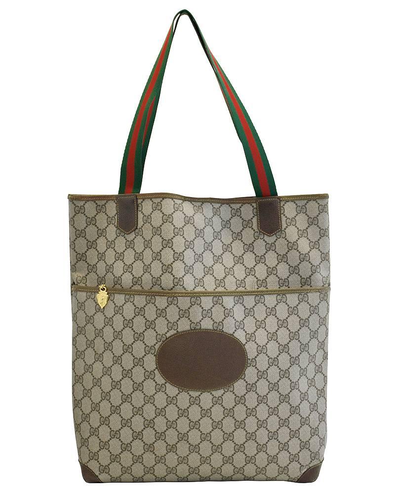 Stunning 1970's Gucci rectangular tote bag. The bag is covered in the classic logo Gucci monogram with Gucci green and red woven striped tape handles. Trimmed and lined in brown leather. Closes with a magnetic snap button. Large outside pocket