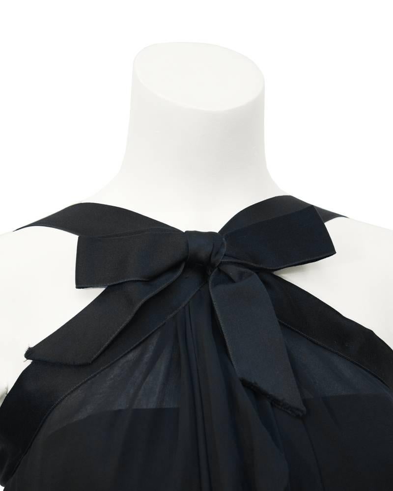 Fabulous 1970's Sarmi demi couture LBD. Silk chiffon overlay trimmed with black satin that finishes in a bow at the center of the neck. Silk chiffon gathers where the bow is placed and cascades down the front of the body. Fitted underslip. Great