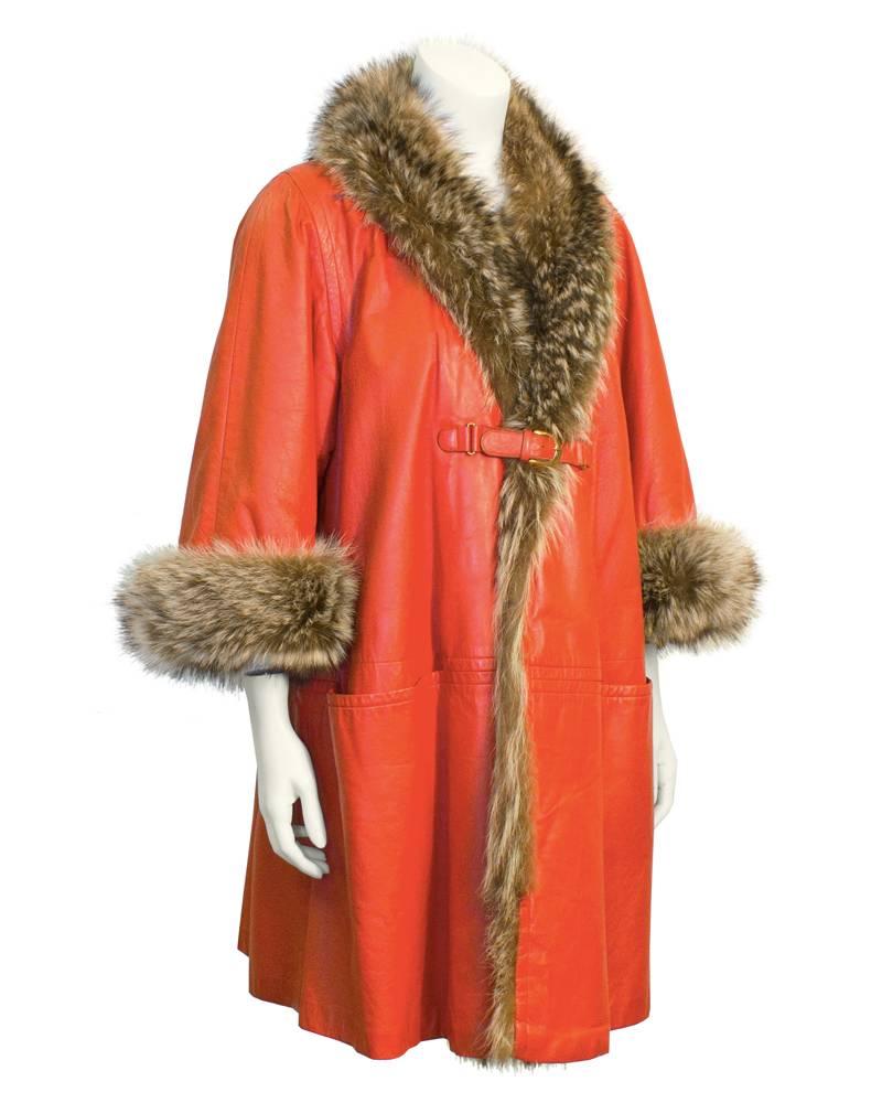 1960's Bonnie Cashin orange leather swing coat. Real racoon fur collar and cuffs. Gold hardware and orange leather buckle closure and large flat front pockets. Faux furry fabric lining makes this a warm winter coat perfect for snowy weather.