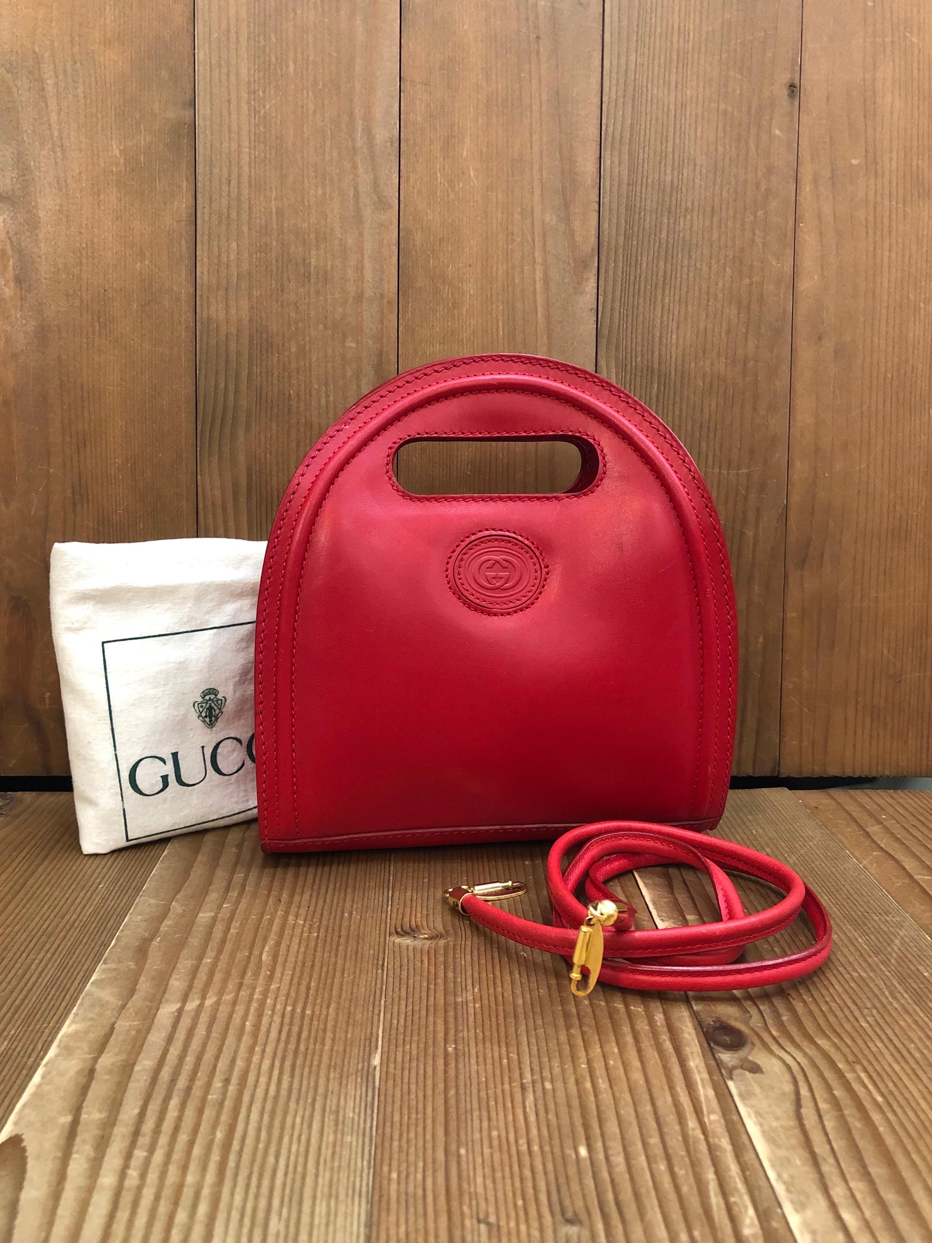 This vintage GUCCI mini book tote crossbody bag is crafted of calfskin leather in red featuring a detachable crossbody strap of the same leather. Magnetic snap closure opens to a nubuck leather interior in red featuring a zippered pocket. Made in