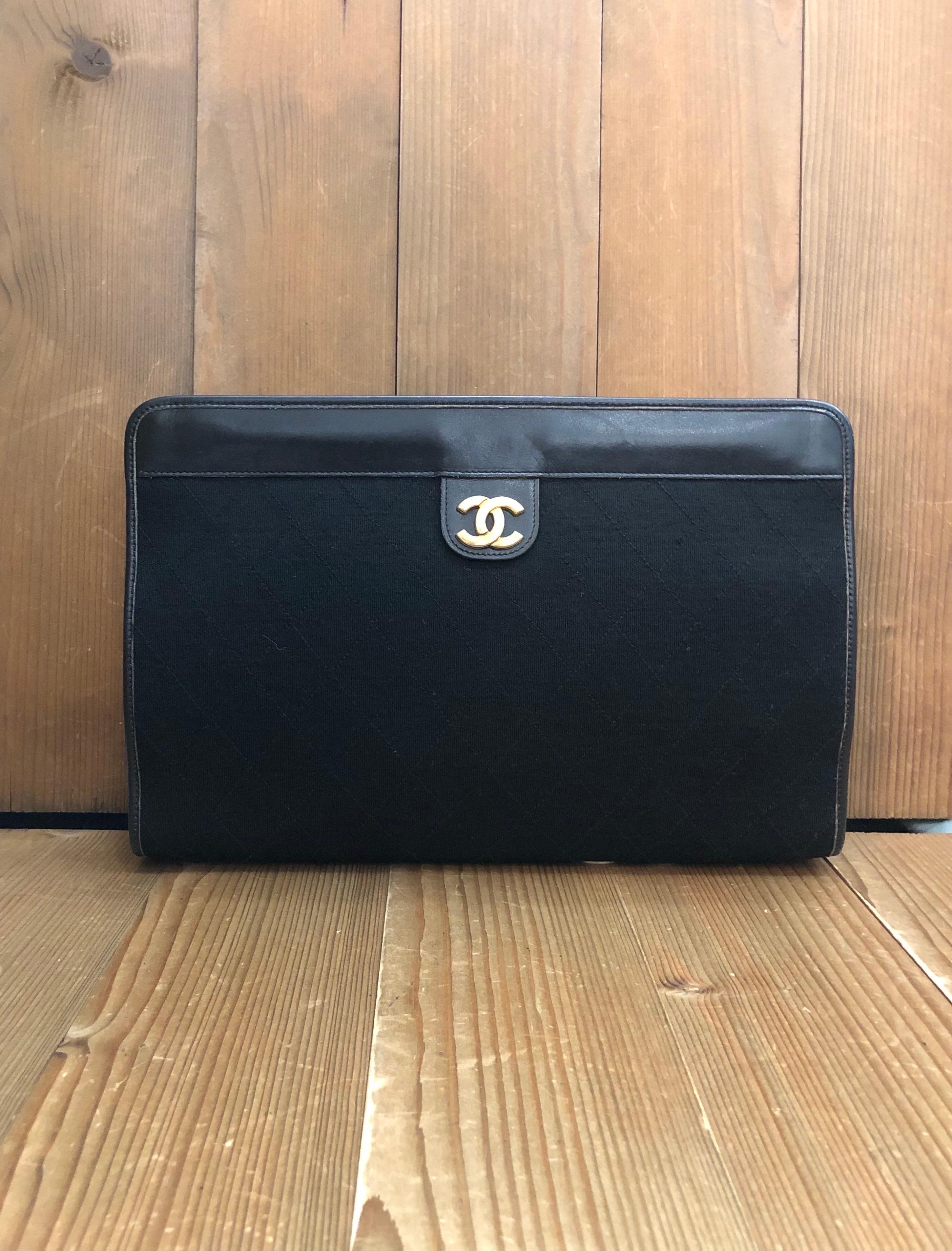 This vintage CHANEL clutch bag is crafted of diamond quilted jersey in black trimmed with black calfskin leather and gold toned hardware. Top spring closure opens to a burgundy lambskin leather interior. Made in France. Measures approximately 11.5 x