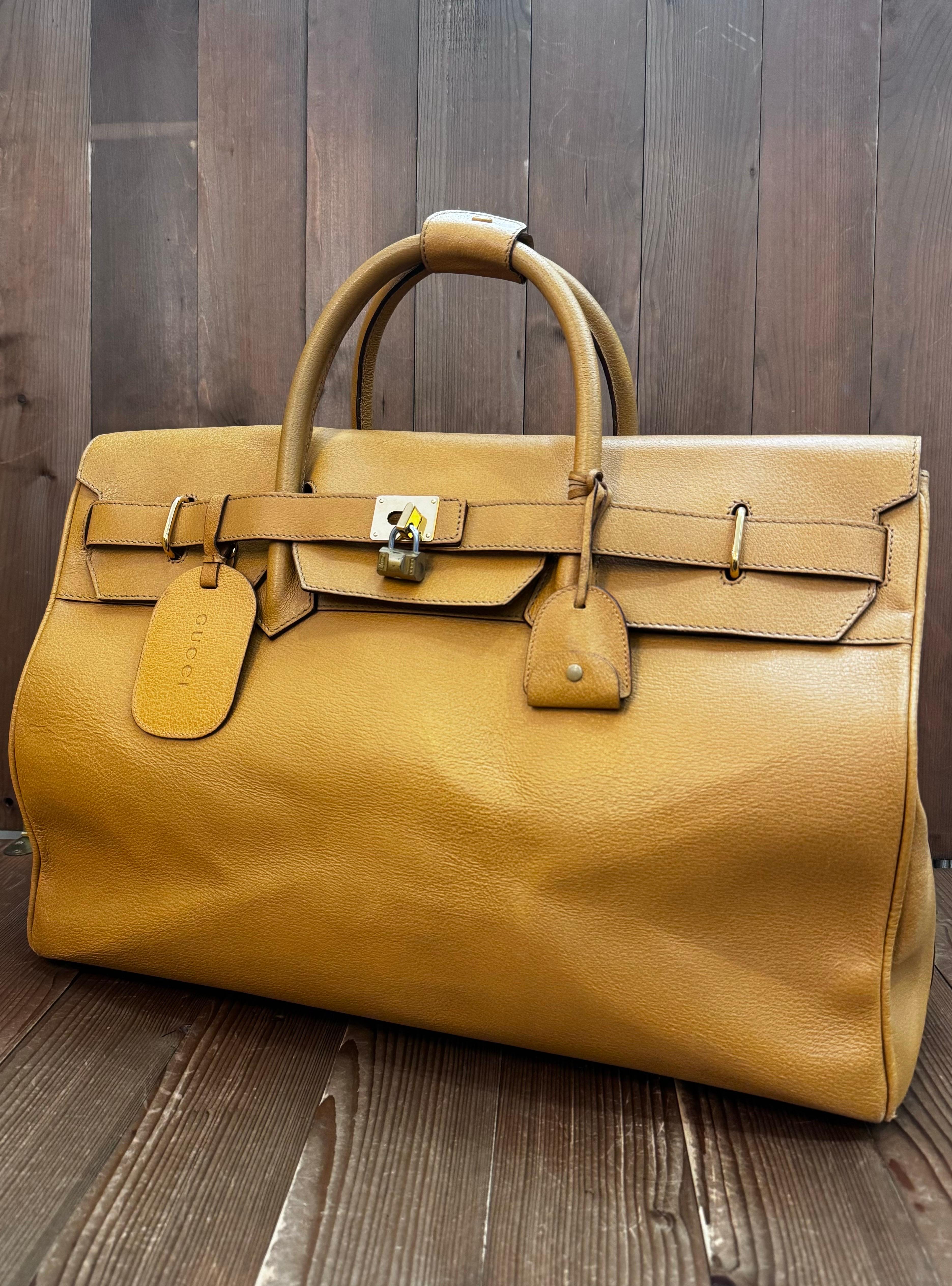 This vintage GUCCI extra large duffle bag is crafted of pigskin leather in mustard yellow featuring gold toned hardware and rolled leather handles. Front flap closure opens to a diamanté jacquard interior featuring a zippered pocket. Made in Italy.