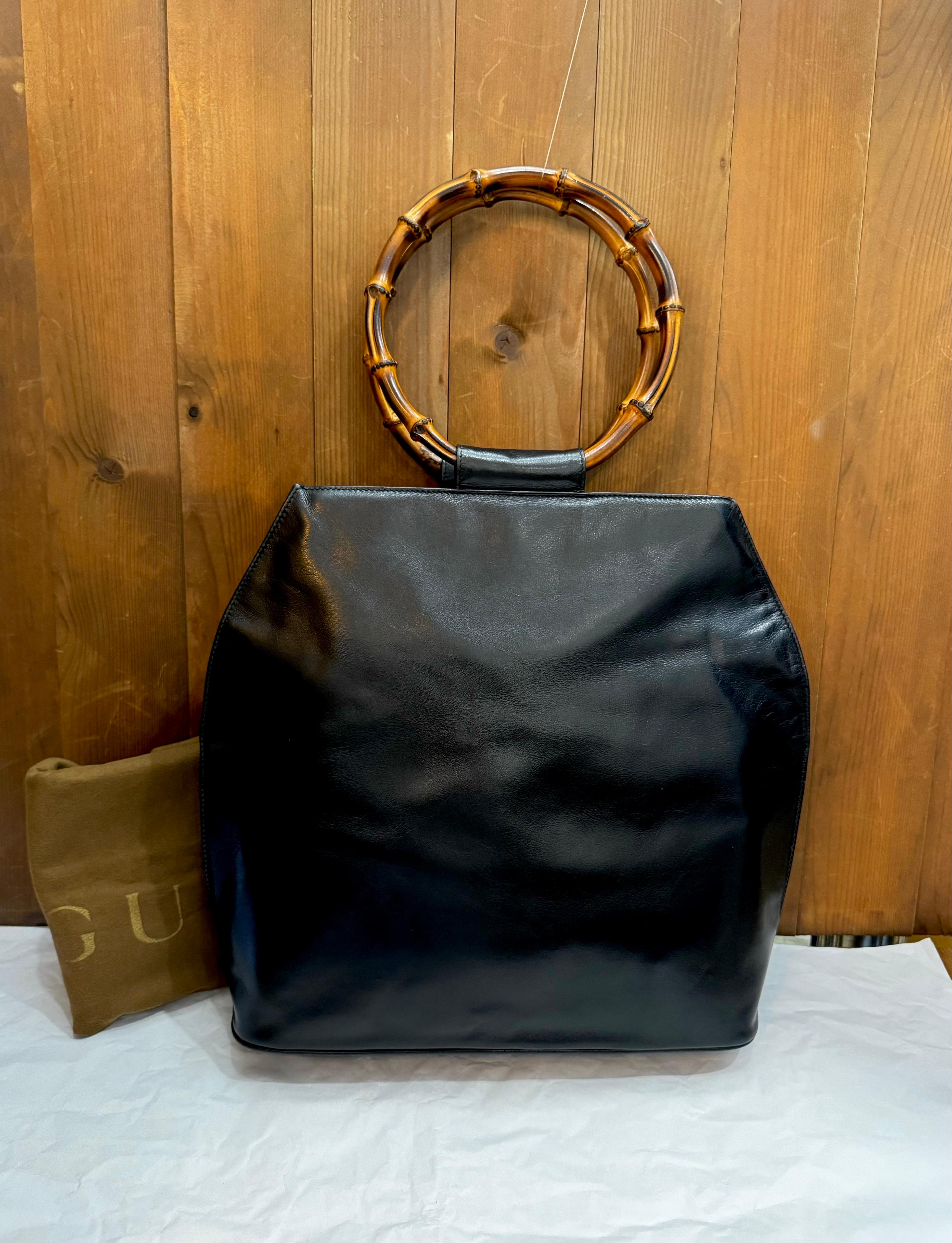 This vintage GUCCI top handle shoulder tote bag is crafted of soft calfskin leather in black featuring two massive bamboo ring handles. Top magnetic snap closure opens to a new interior in black featuring a zippered pocket. Made in Italy. Measures