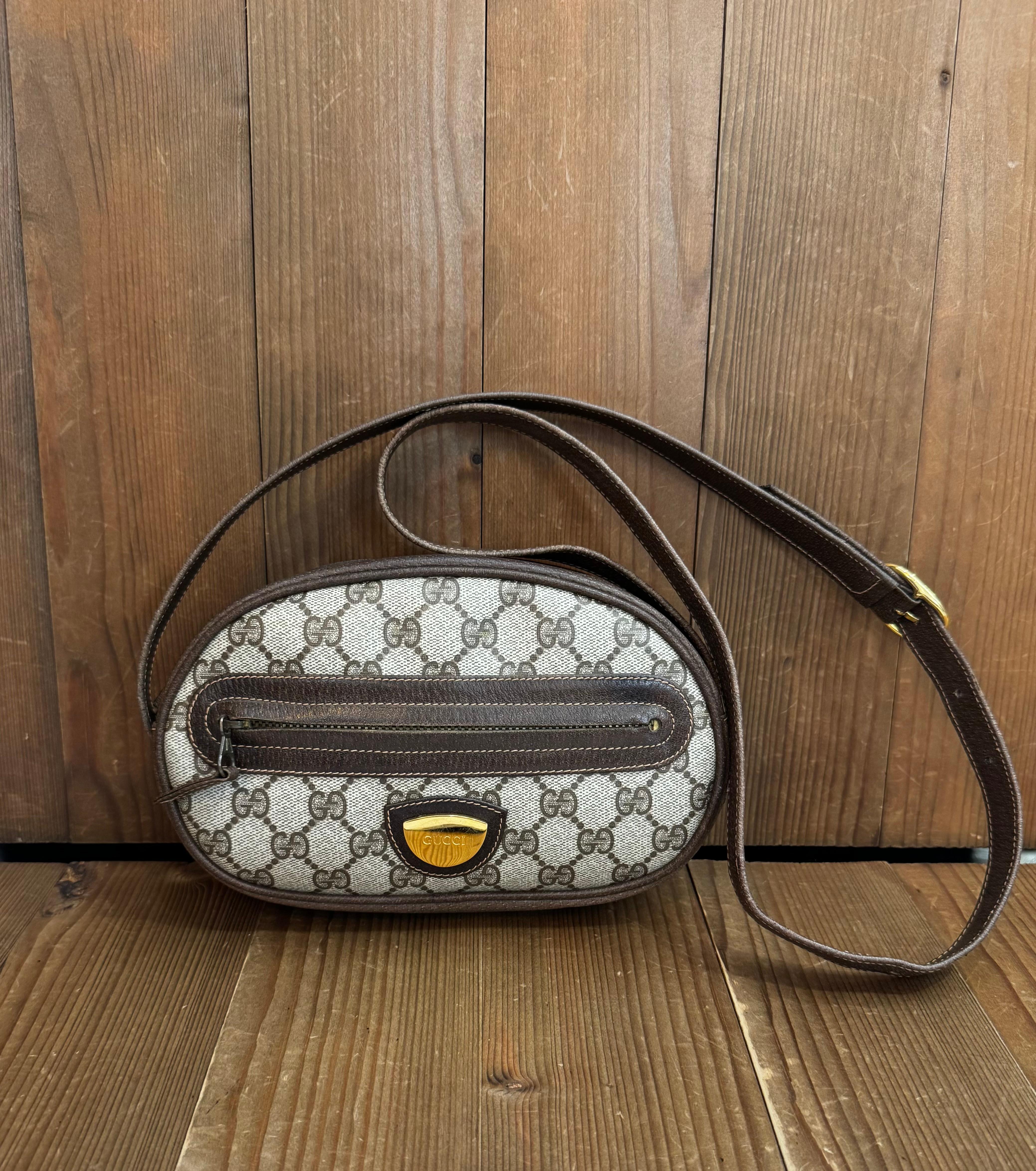 Ce sac à bandoulière vintage GUCCI est réalisé en toile enduite du monogramme GG et en cuir de porc de couleur marron, avec des ferrures dorées. La fermeture à glissière sur le dessus ouvre sur un intérieur enduit qui a été nettoyé par des
