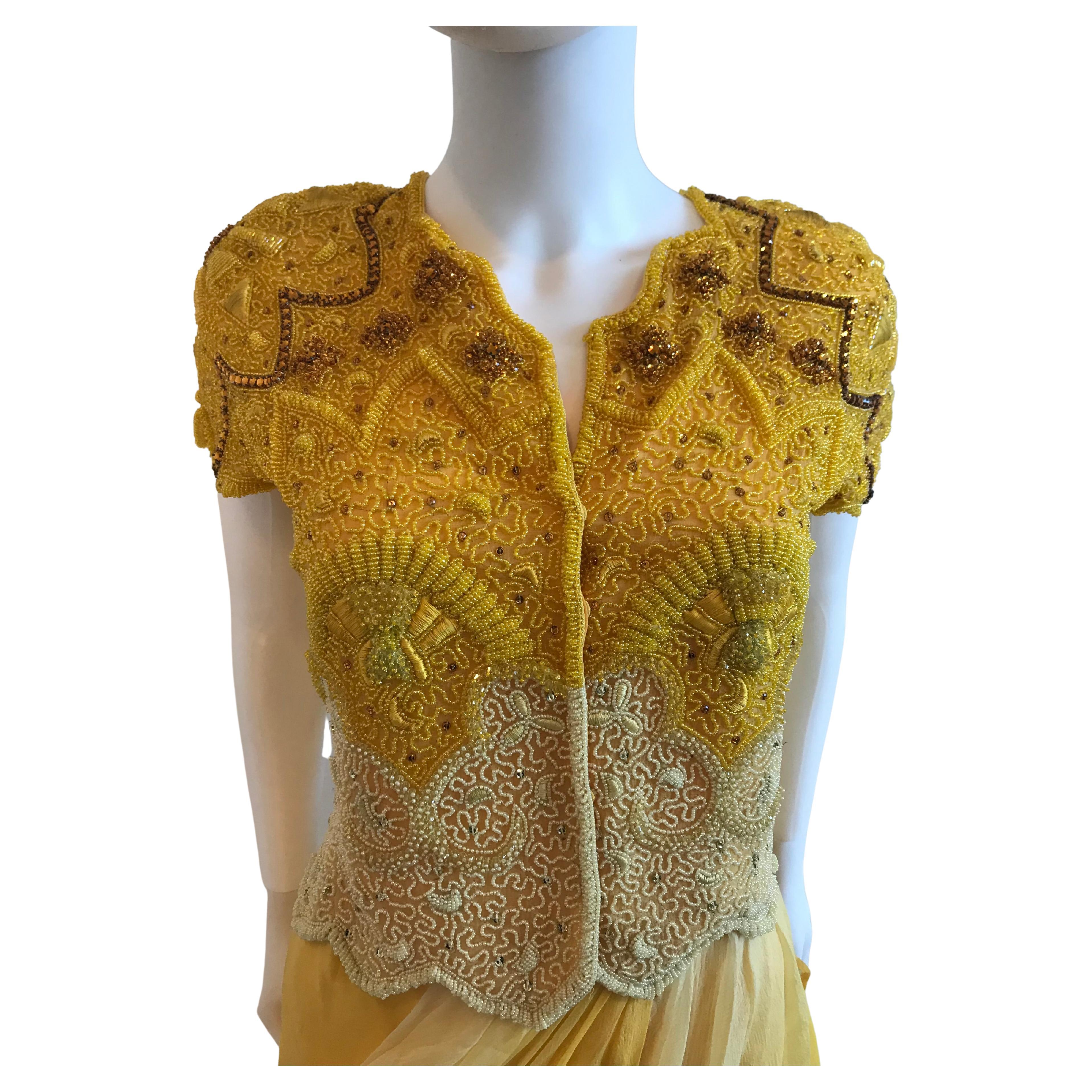 This rare and glamorous Genny by Gianni Versace Yellow Bolero and Chiffon Skirt Set features beaded diamond embroidery. The Bolero  is short sleeved and the skirt features draped Silk Chiffon.
Designer Label Removed. Size US 10. Made in Italy. 100%