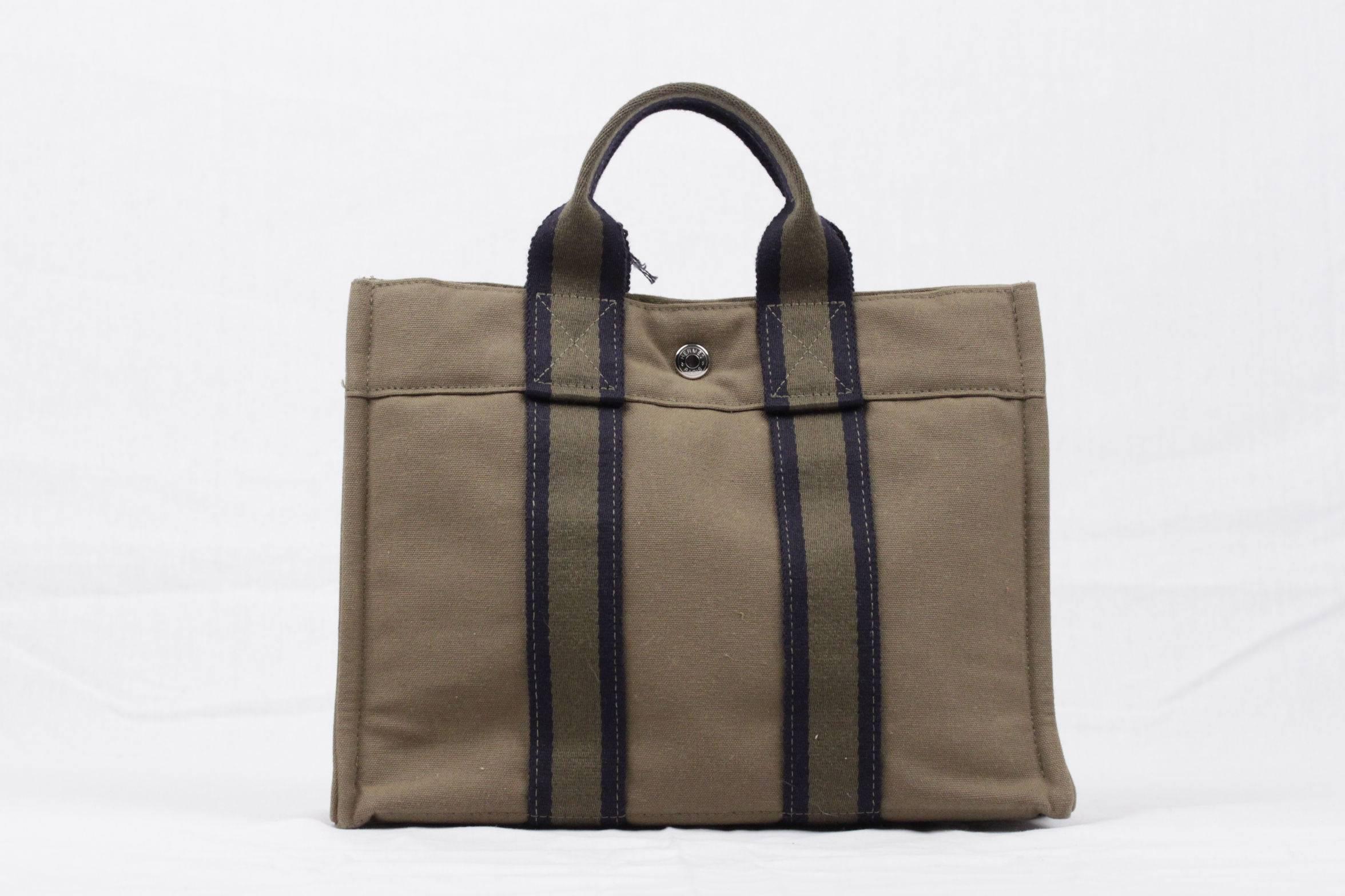 
- Model: 'FOURRE TOUT - PM' Tote handbag

- Made in France

- Miltary Green/Navy blue color

- Material: 100% cotton canvas

- It has snaps on both ends for expansion a

- Durable canvas that is perfect for casual and everyday use.
-