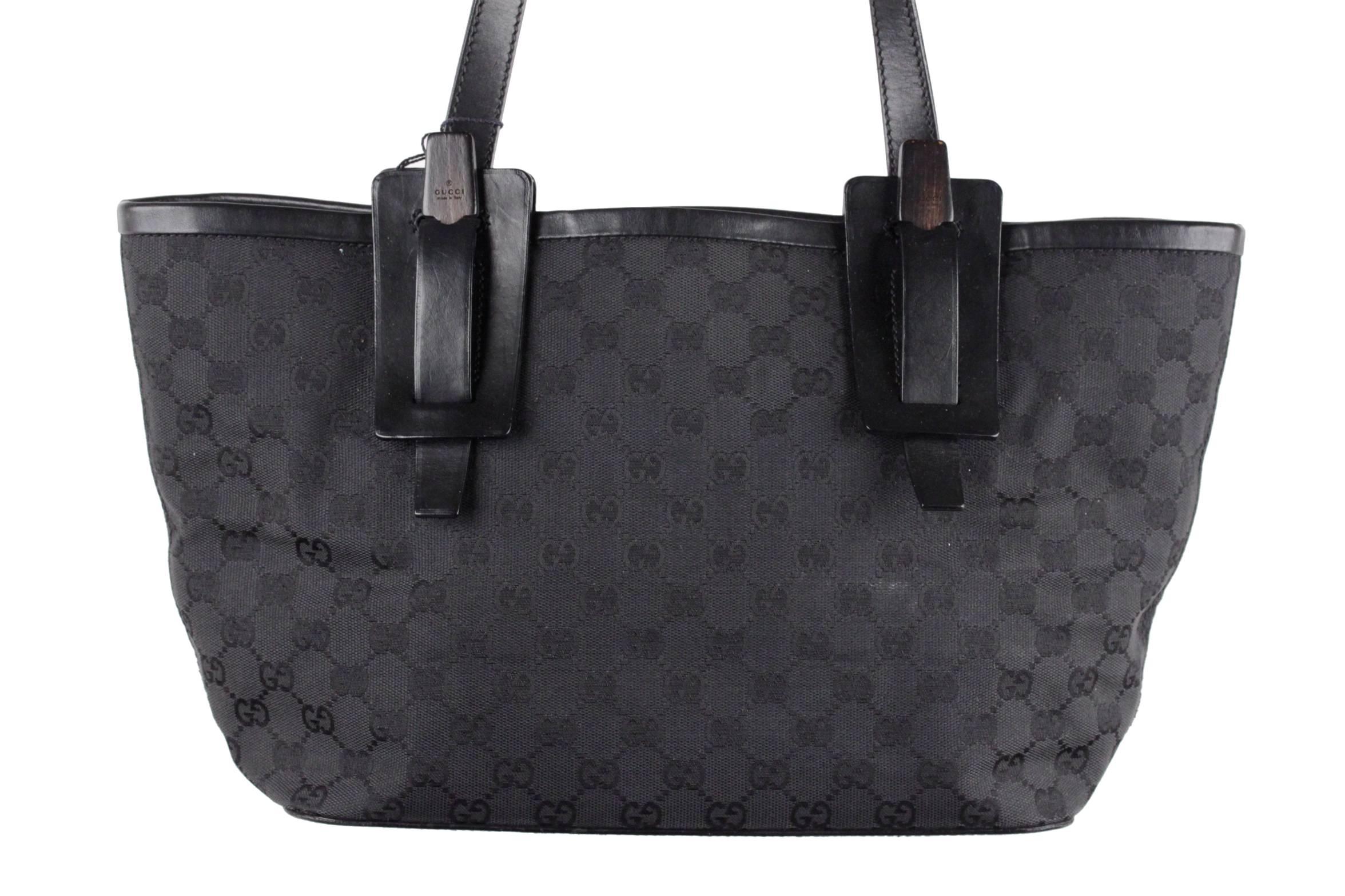 
- Crafted in black GG monogram canvas with leather trim
- Wooden pieces with GUCCI logo where the strap attache
- Black canvas lining
- 1 side zip pocket inside
- Open top
- Approx. measurements: 8 3/4 x 16 1/2 x 4 1/2 inches - 22,2 x 41,9 x