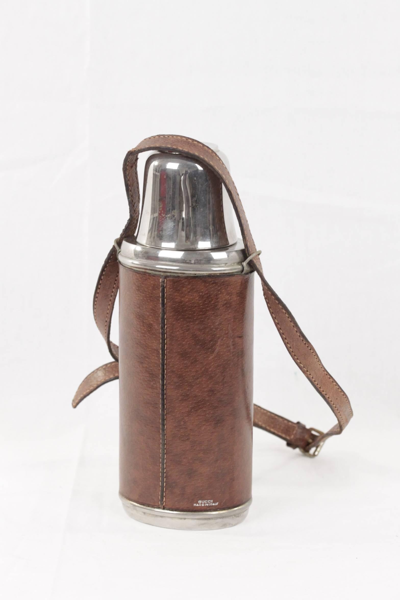 - Vintage Vacuum flask/Thermos stainless steel by GUCCI with metal lid

- The top unscrews and is a cutie cup

- It closes with a cork

- Brown pigskin leather exterior

- Adjustable and removable shoulder strap

- Height: 10 1/2 inches -