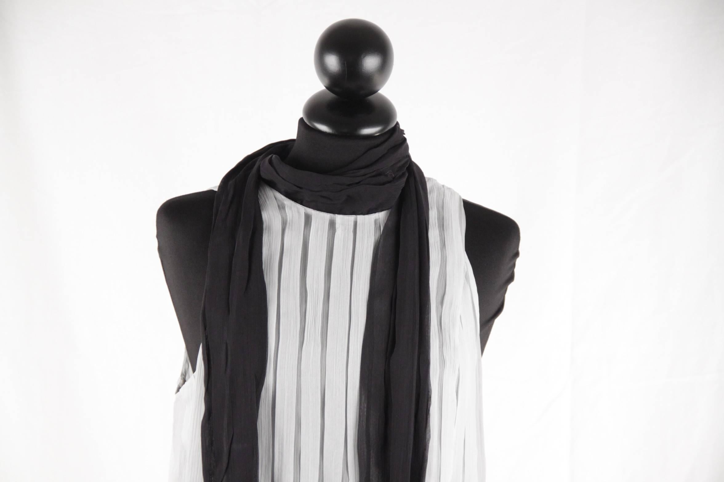 

- Composition: 100% Silk

- Baby blue/Light Gray sheer fabric

- Black contrast self-tie scarf on the neckline

- Side zip and hook and eye closure

- Allover box pleating

- Size: 38 (The size shown for this item is the size indicated