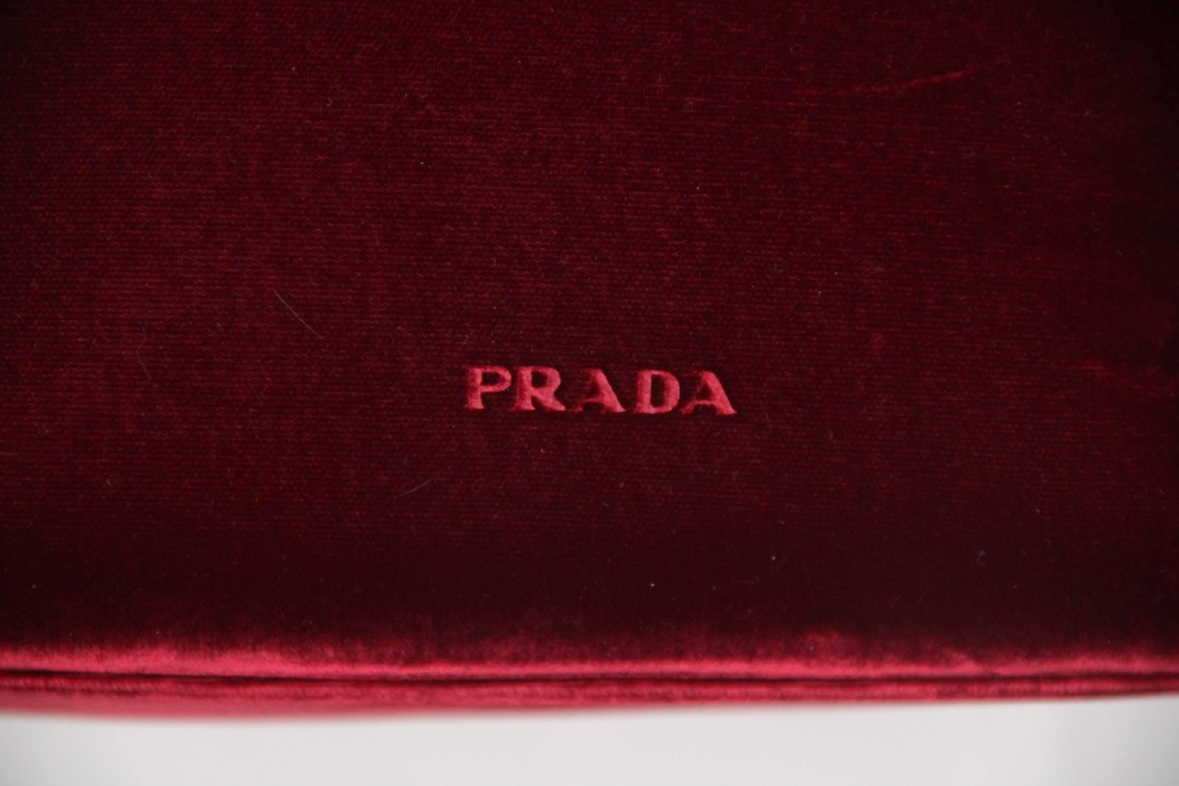 - Red velvet frame handle bag by PRADA
- PRADA signature engraved on the front
- Upper clasp closure
- Black fabric lining with PRADA signatures
- 1 side zip pocket inside 
- Measurements of the purse: 7 x 10  x 4 inches - 17,7 x 25,4 x 10,2